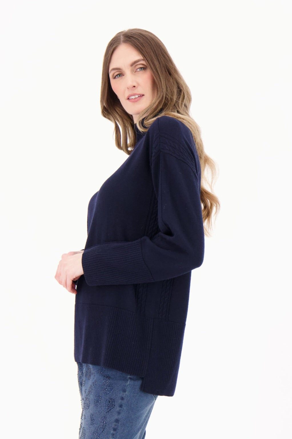 Woman wearing a navy sweater and blue jeans on a white background
