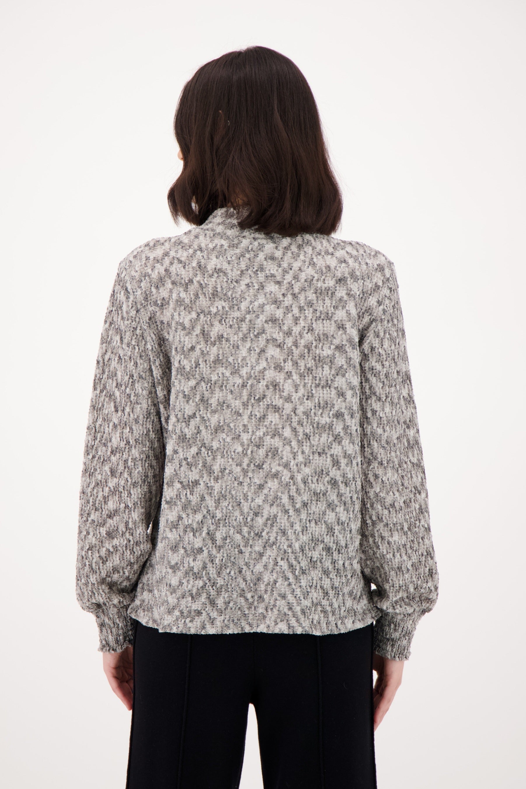 Person wearing a patterned shirt from behind on a white background