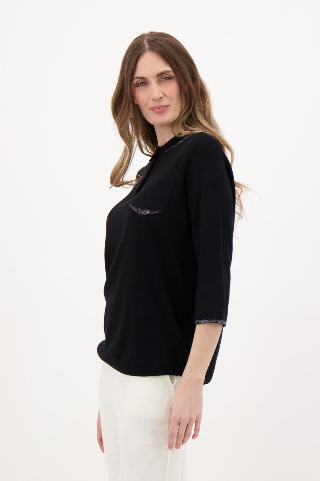 Woman wearing a black top and white pants on a white background