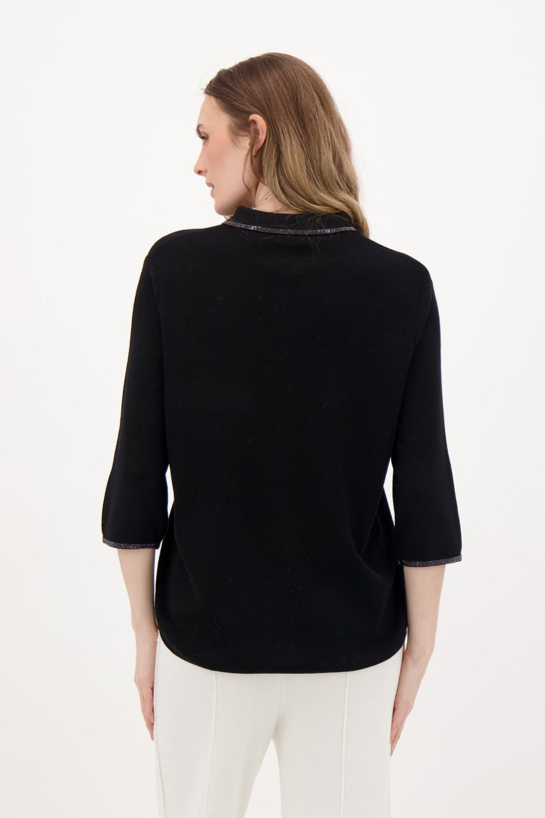 Woman wearing a black top and white pants on a white background