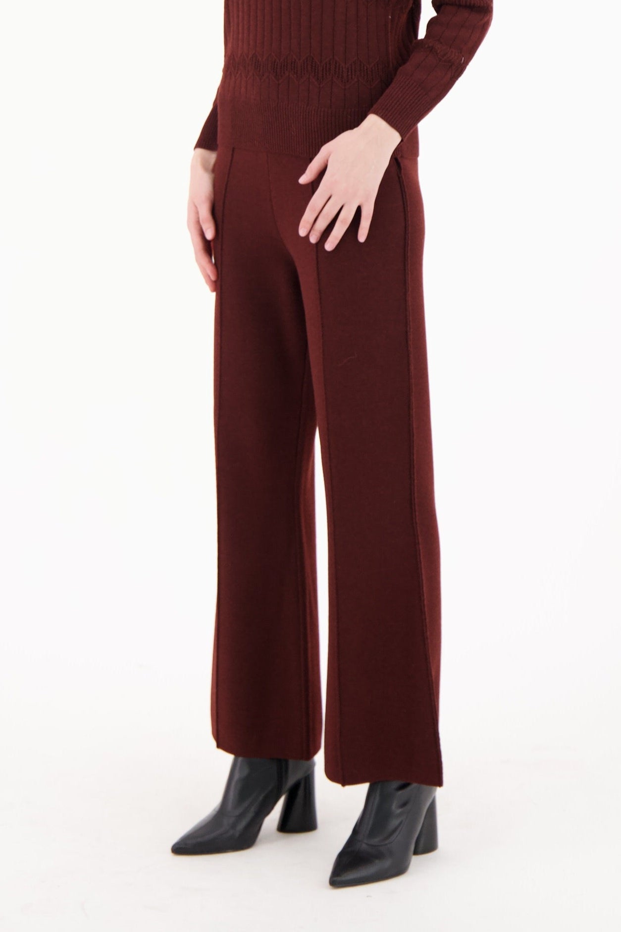 Woman wearing a burgundy knit jumpsuit on a white background