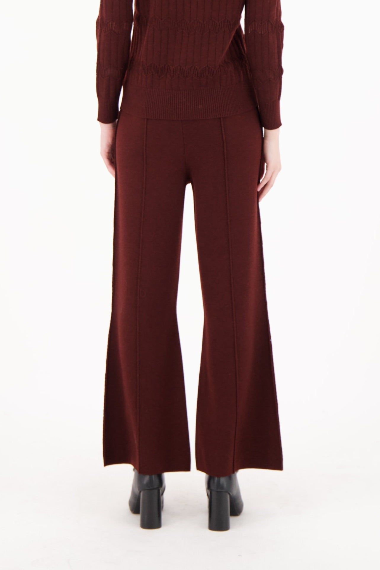 Woman wearing a maroon jumpsuit on a white background