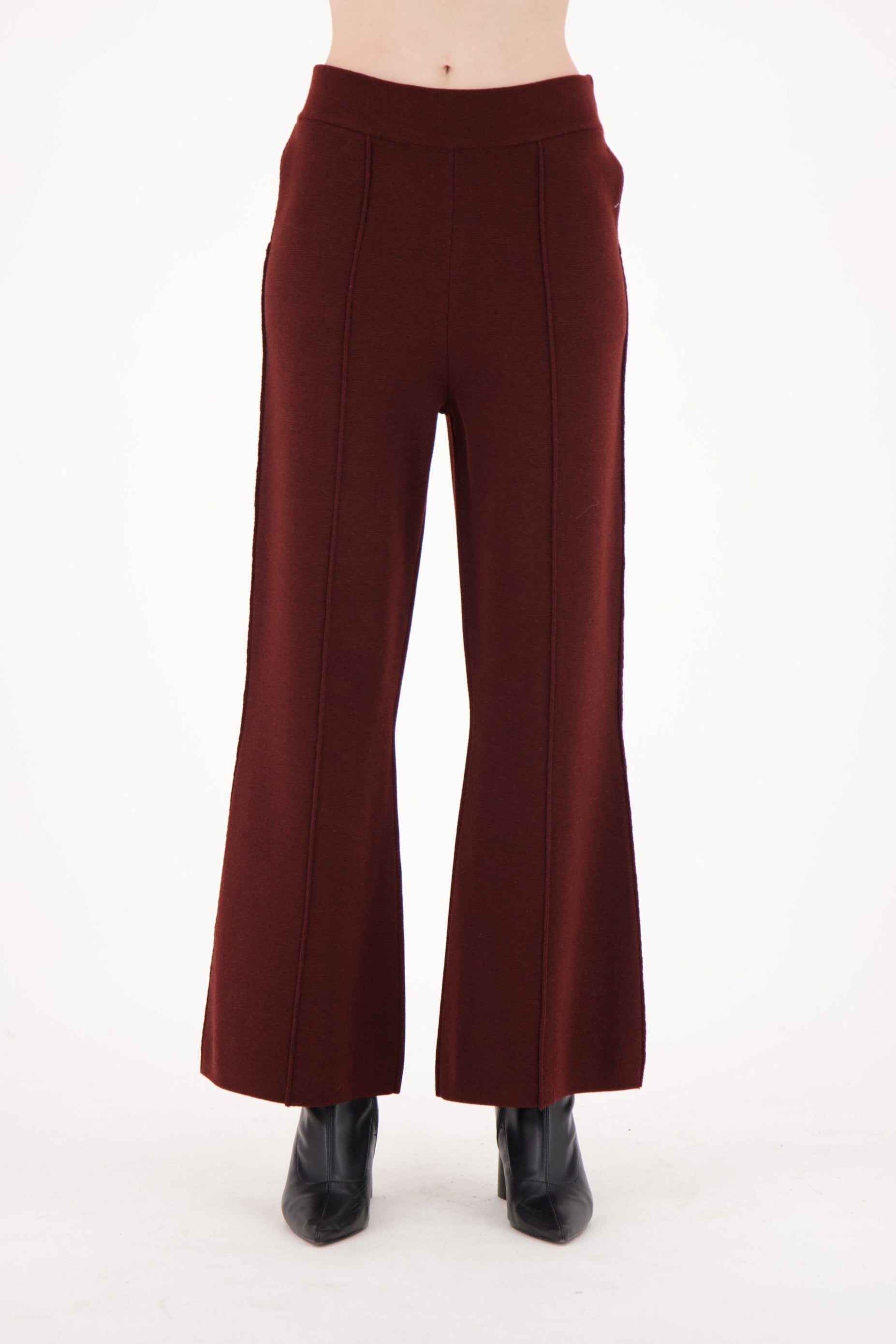 Maroon flared pants worn by a person on a white background