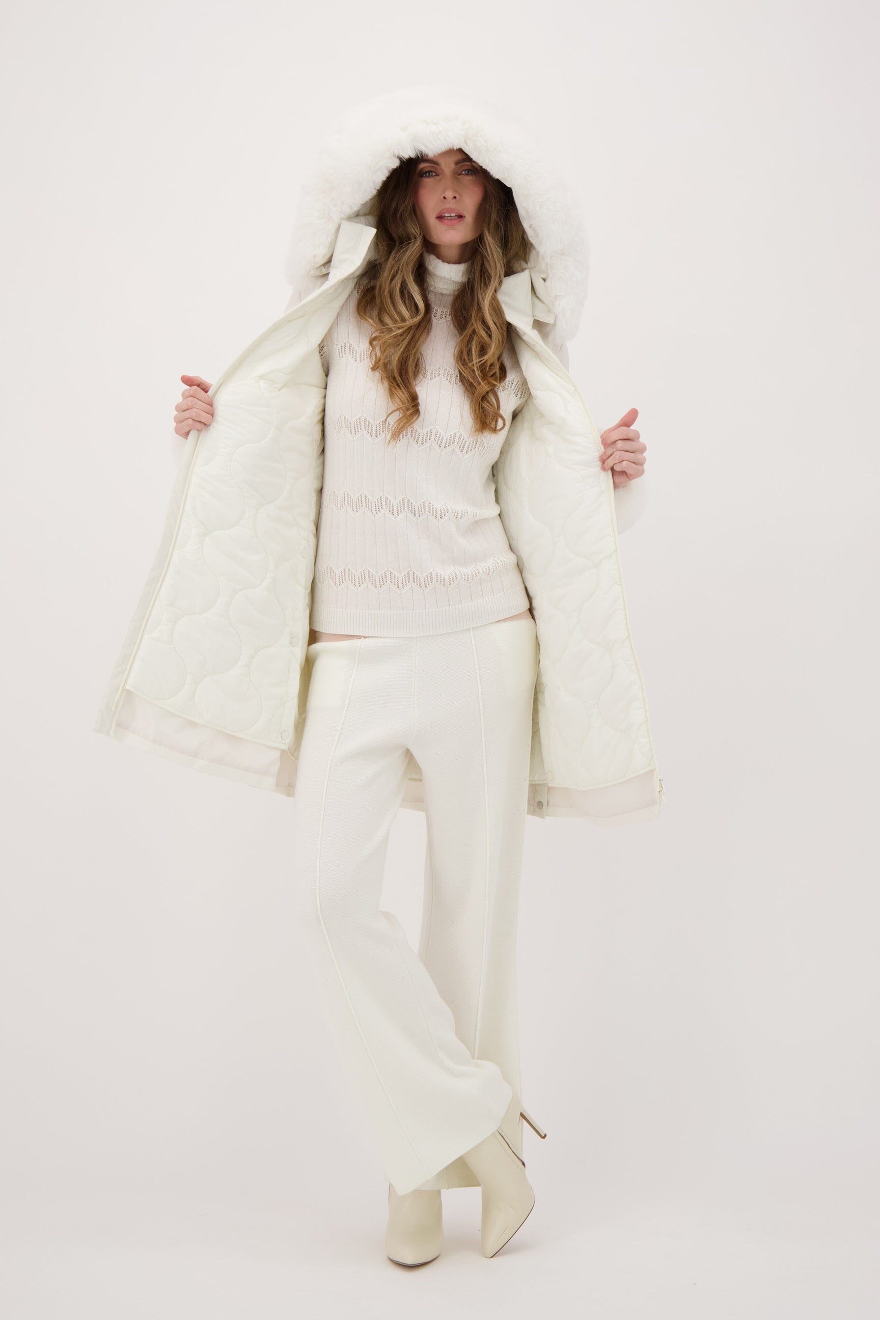 Person wearing a white puffer coat and pants on a white background
