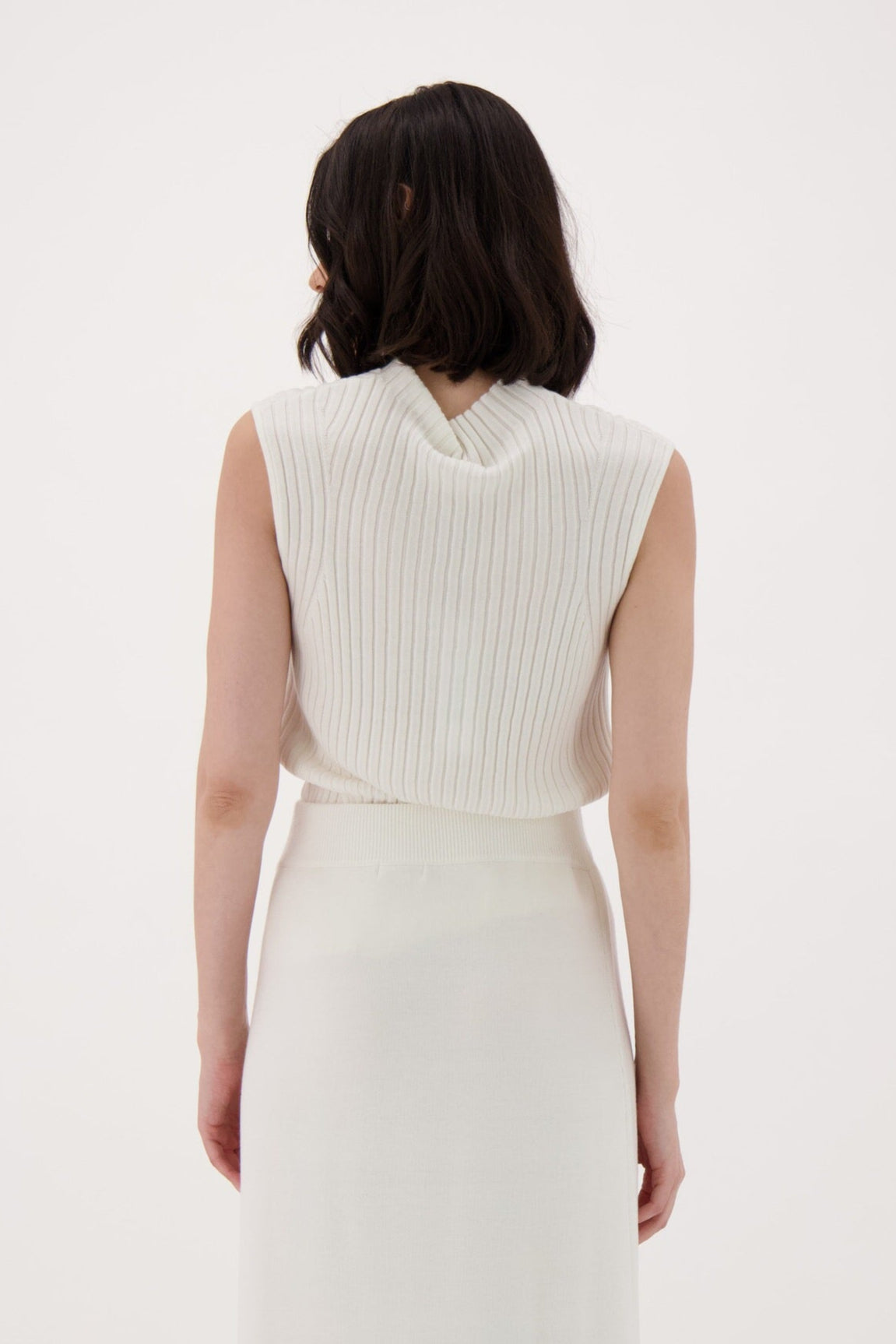 Woman wearing a white sleeveless dress with a belt on a white background