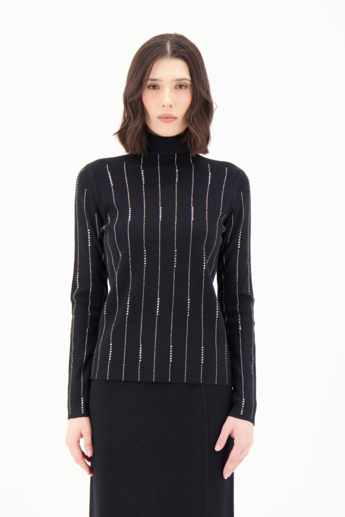 Woman wearing a black turtleneck sweater with white vertical stripes on a white background