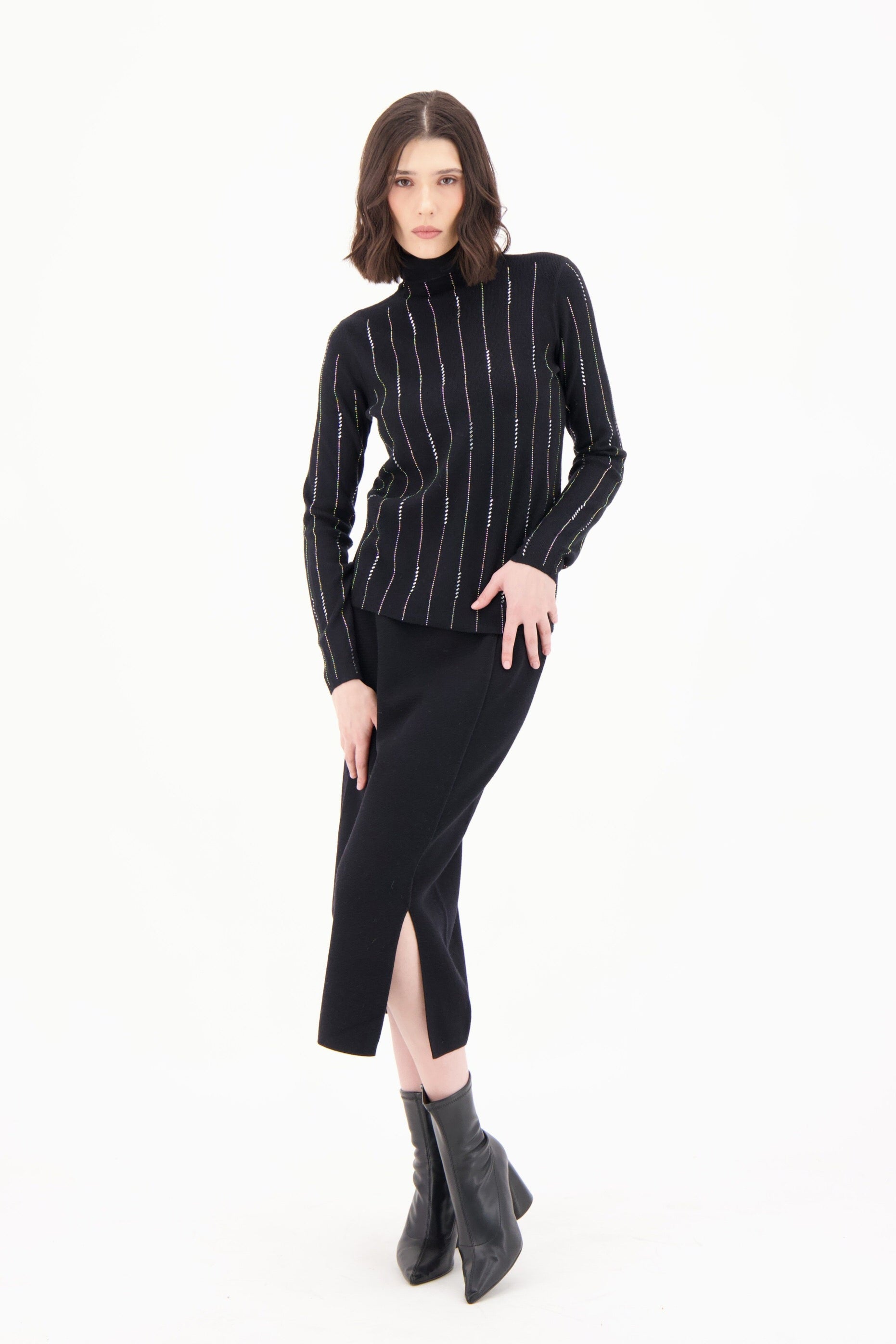Woman wearing a black pinstripe turtleneck sweater and black skirt with a white background