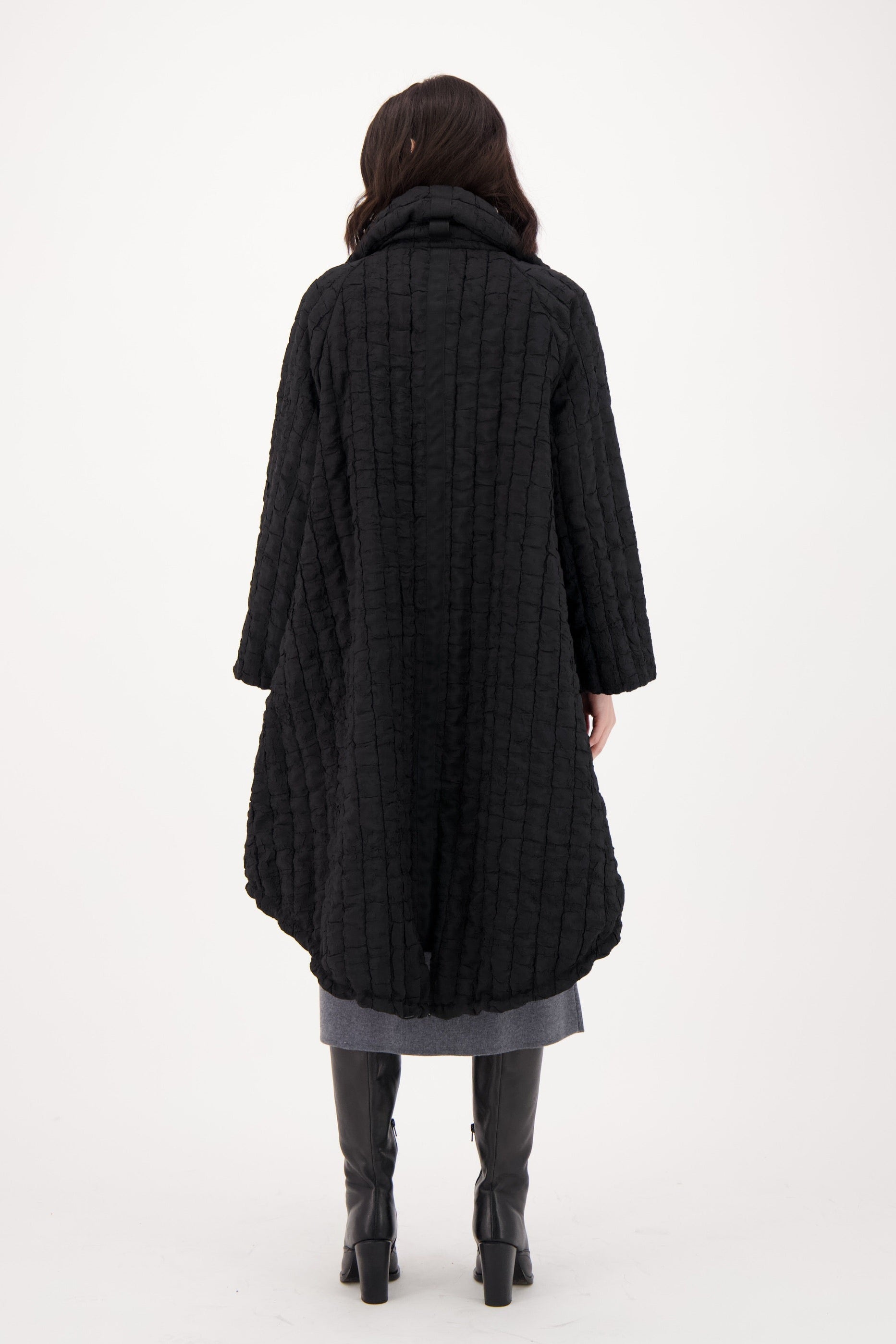 Person wearing a long dark coat on a white background