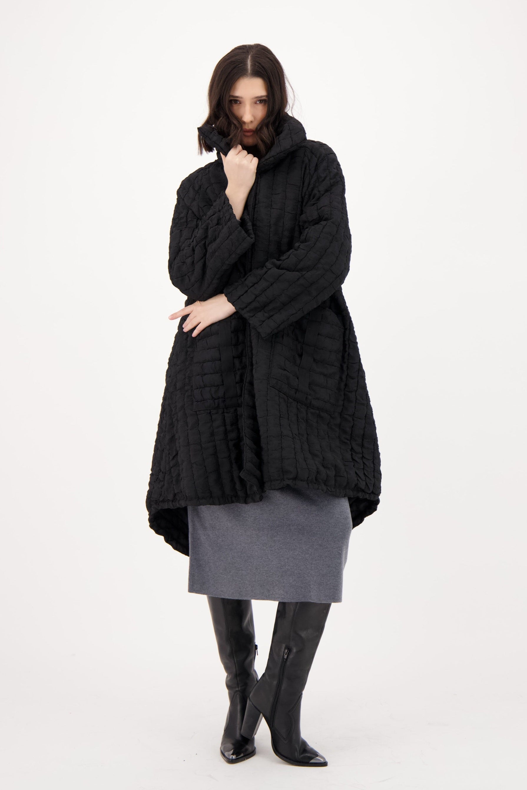 Person wearing a long black coat on a white background