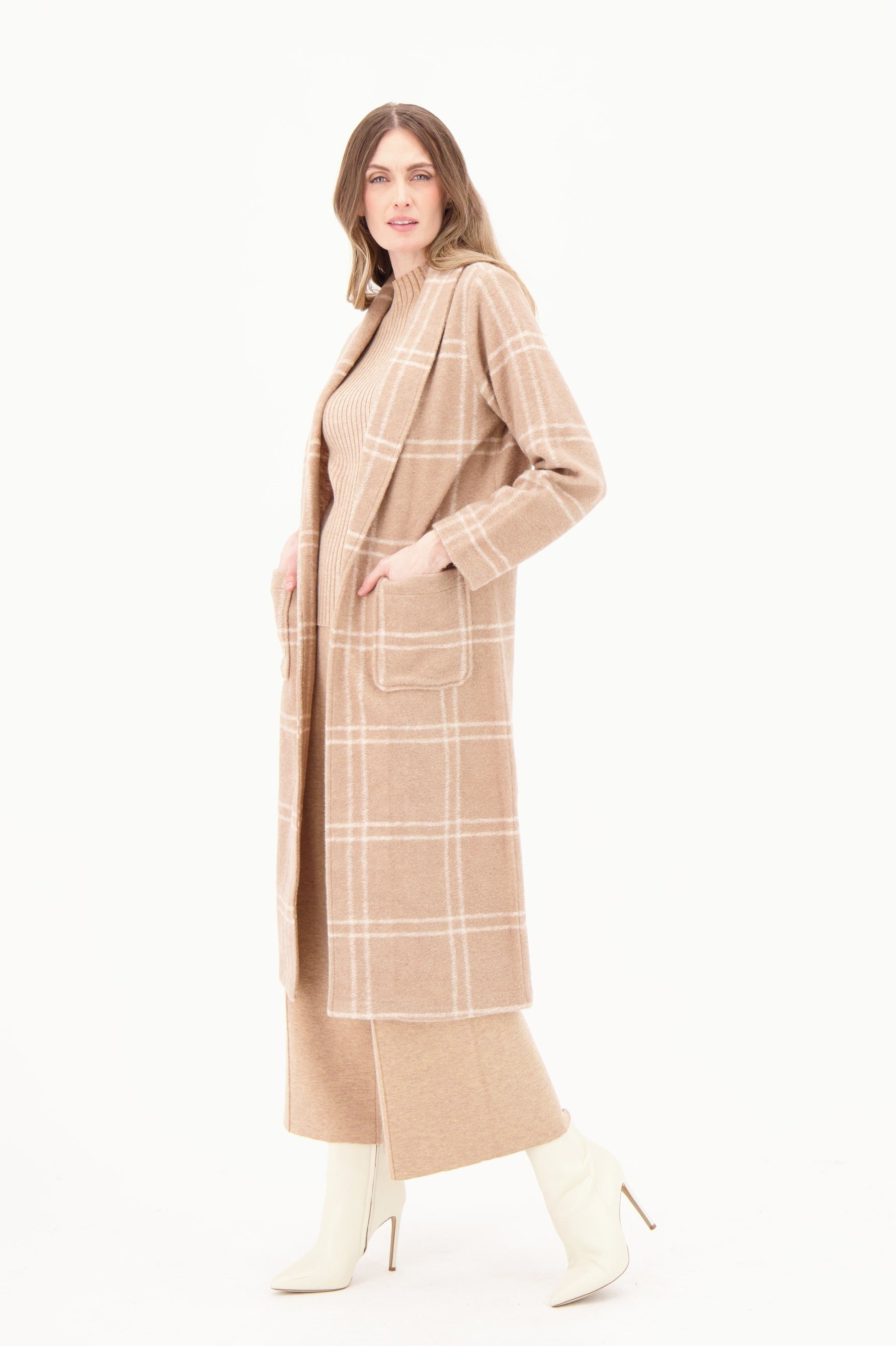 Woman wearing a long beige checkered coat on a white background