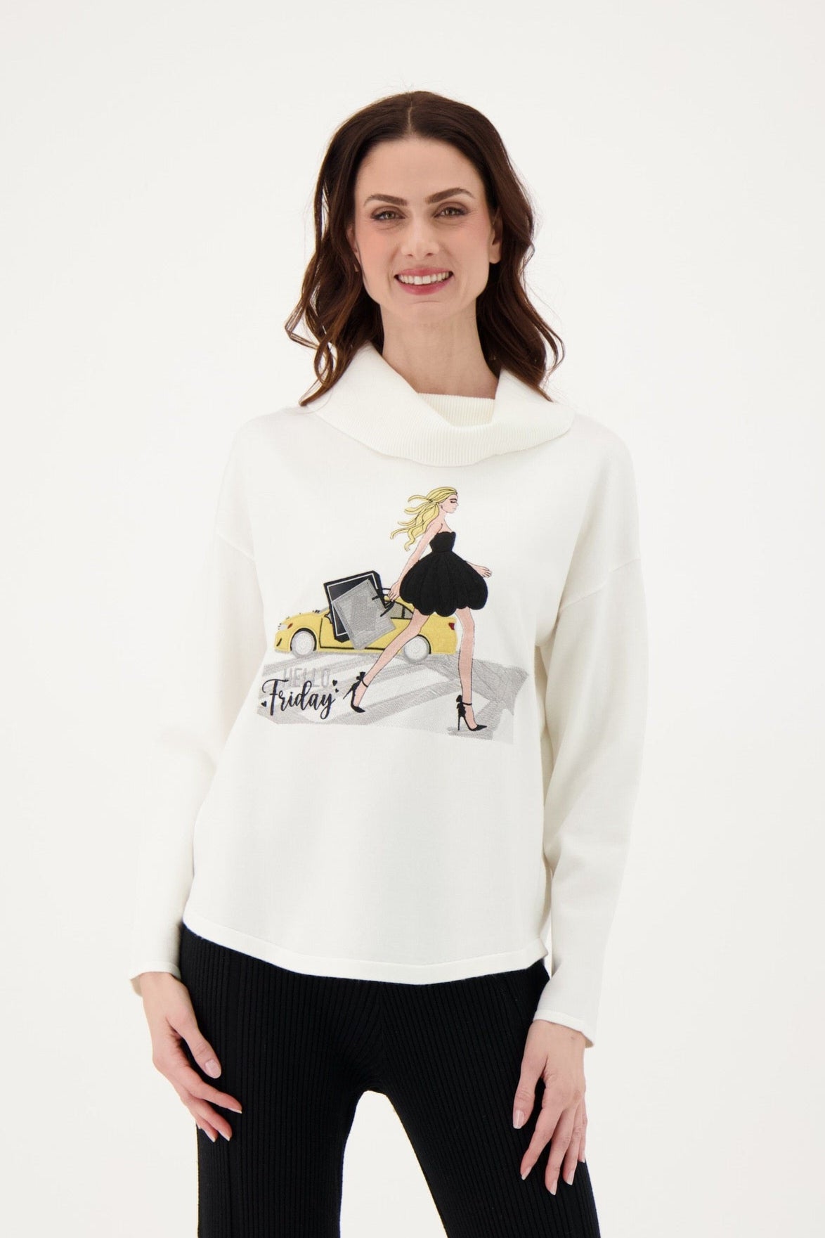 Woman wearing a white sweater with a graphic design and black pants on a white background
