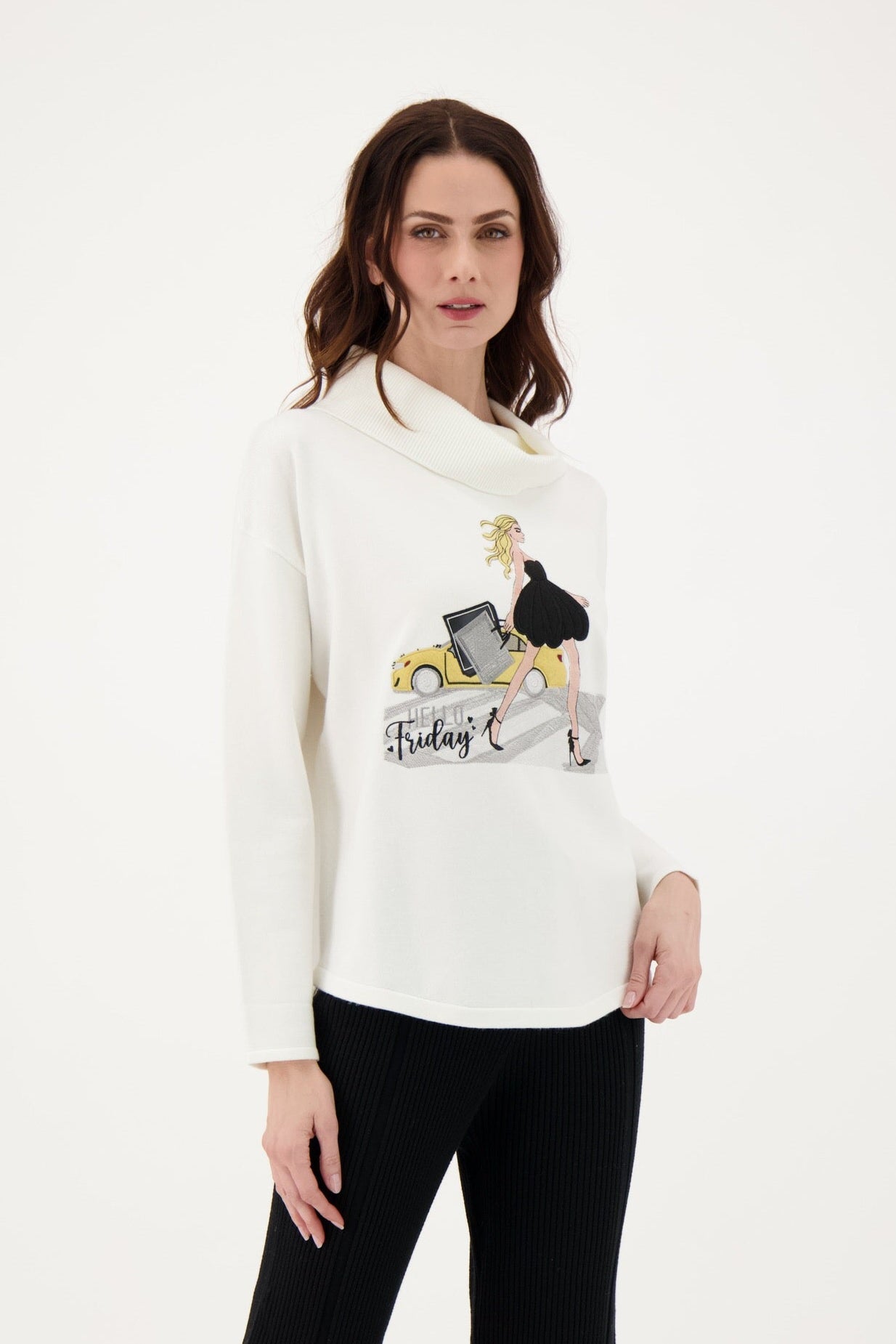 Woman wearing a white sweater with a graphic design and black pants on a white background