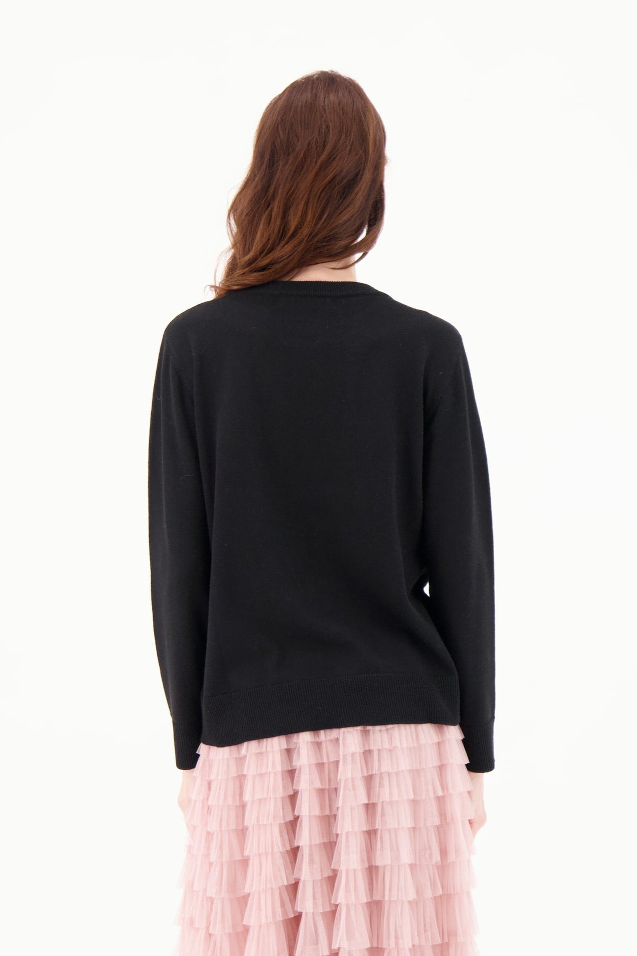 Person wearing a black sweater and pink ruffled skirt on a white background