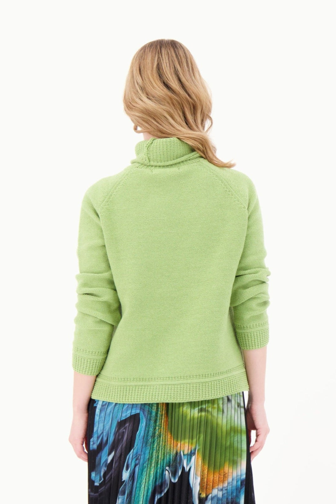 Woman wearing a light green sweater with a colorful skirt on a white background
