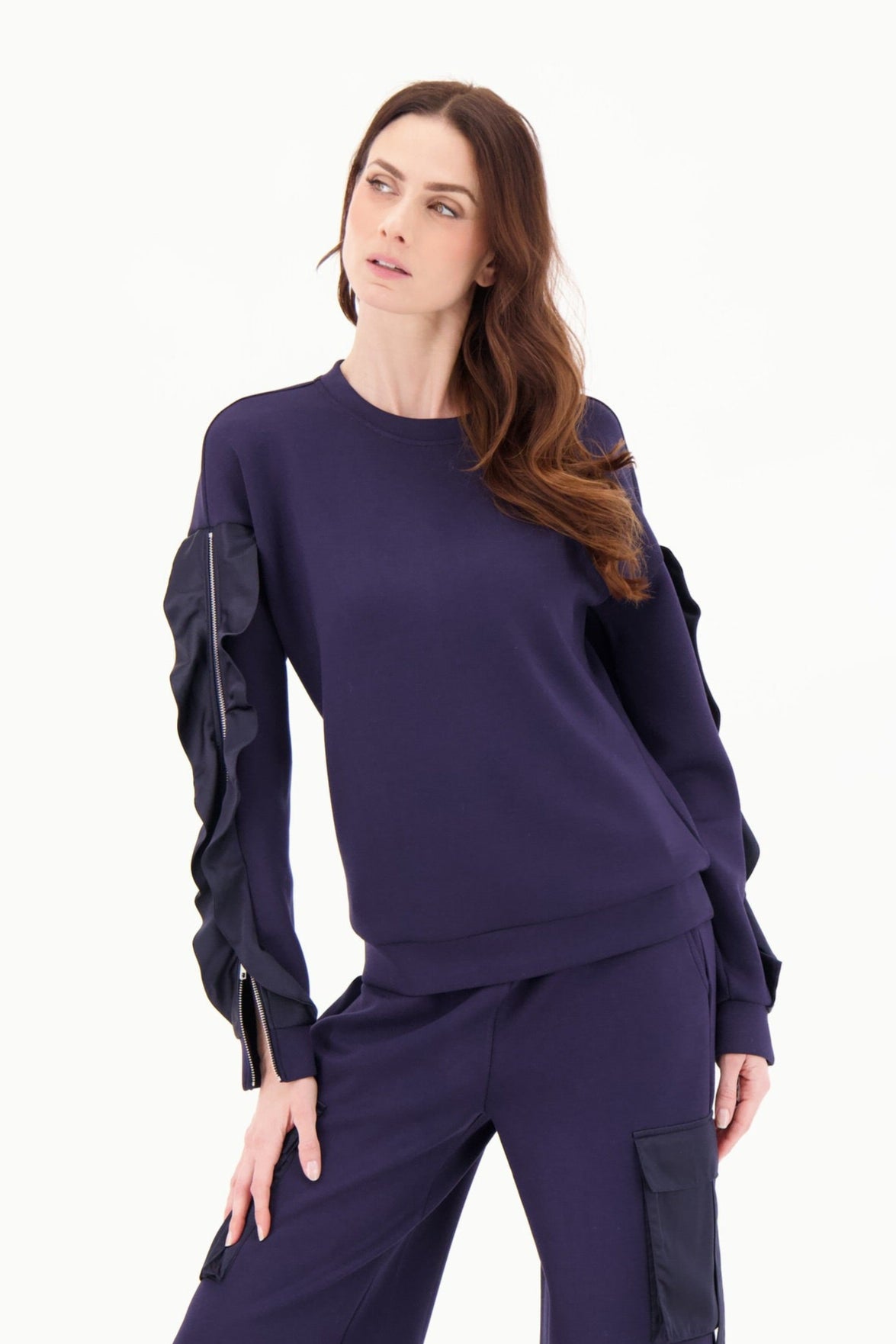 Woman wearing a navy outfit with long sleeves and wide-leg pants on a white background