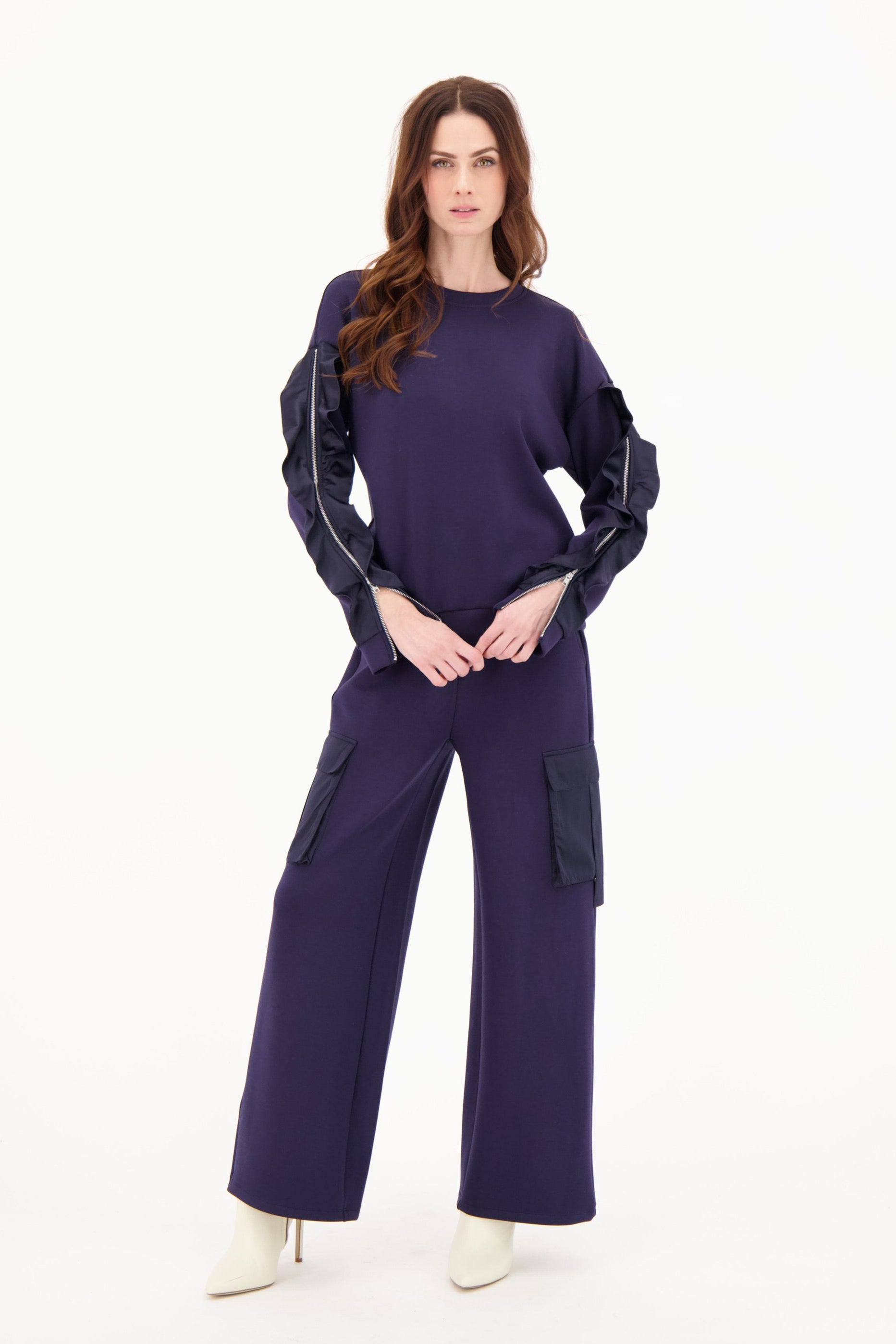 Woman wearing a dark purple outfit with reflective accents on a white background