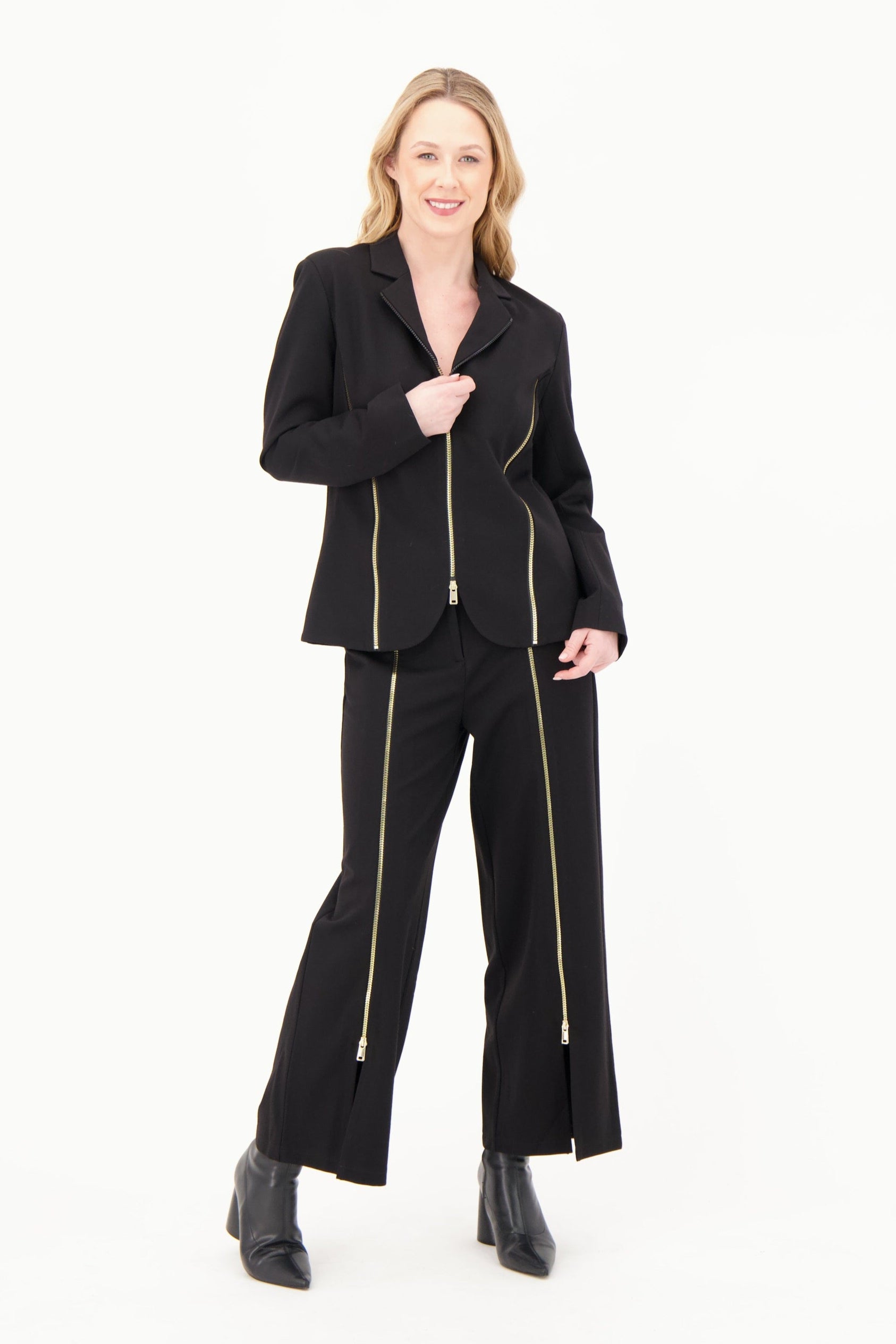 Woman wearing a black suit with gold zippers on a white background