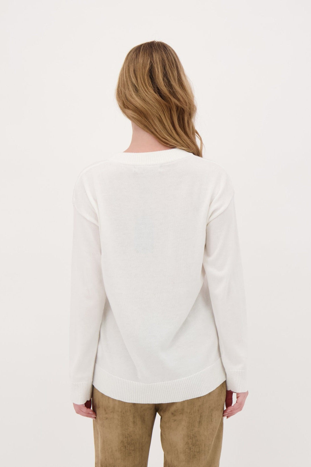 Person wearing a white sweater and beige pants on a white background