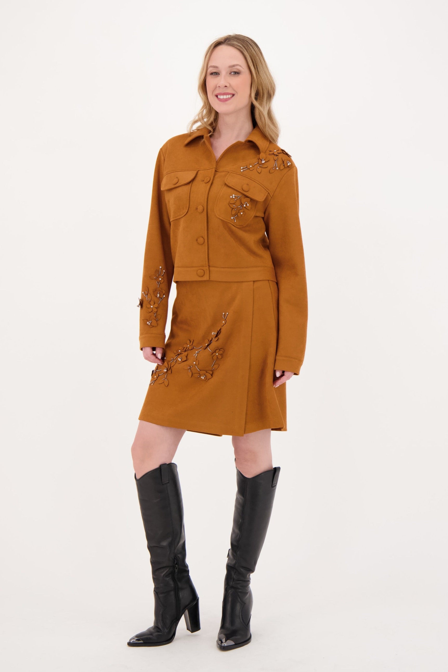 Woman wearing a brown dress with black knee-high boots on a white background