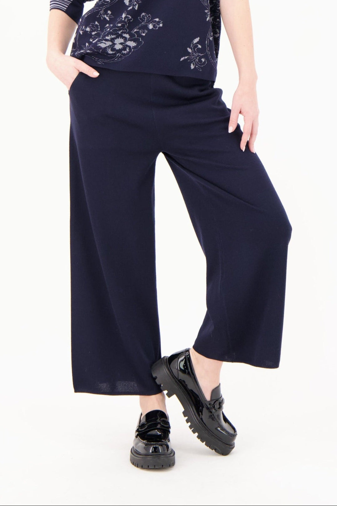 Person wearing navy blue wide-leg pants and black shoes on a white background