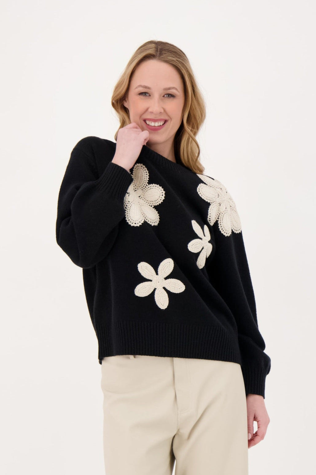 Woman wearing a black sweater with white floral patterns on a white background