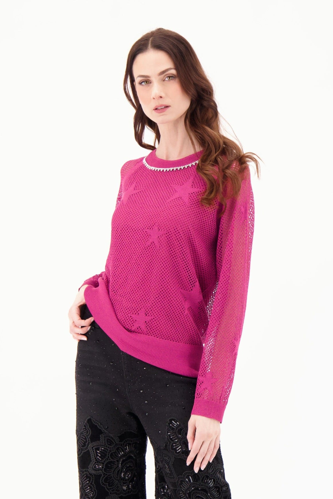 Woman wearing a pink sweater and black pants on a white background