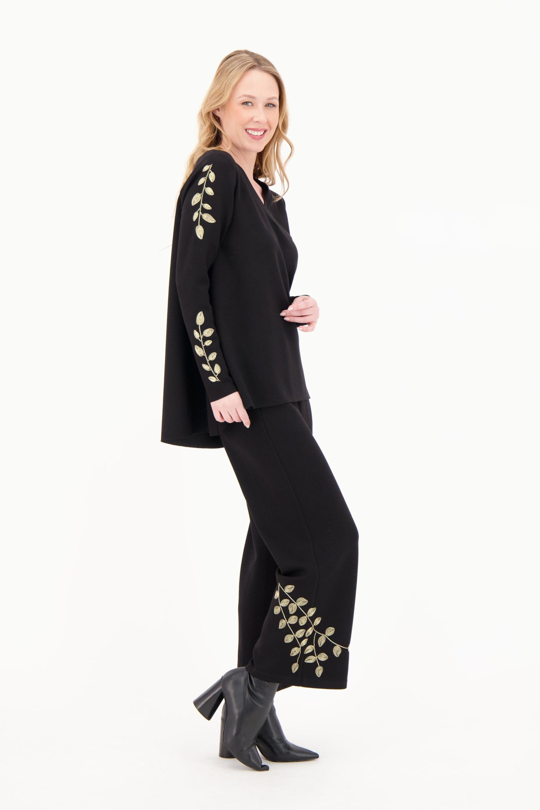 Woman wearing a black outfit with gold embroidery on a white background
