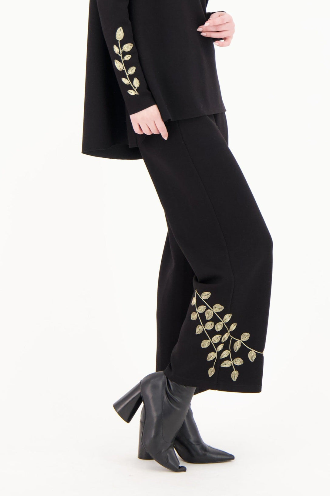 Woman wearing a black outfit with gold embroidery on a white background