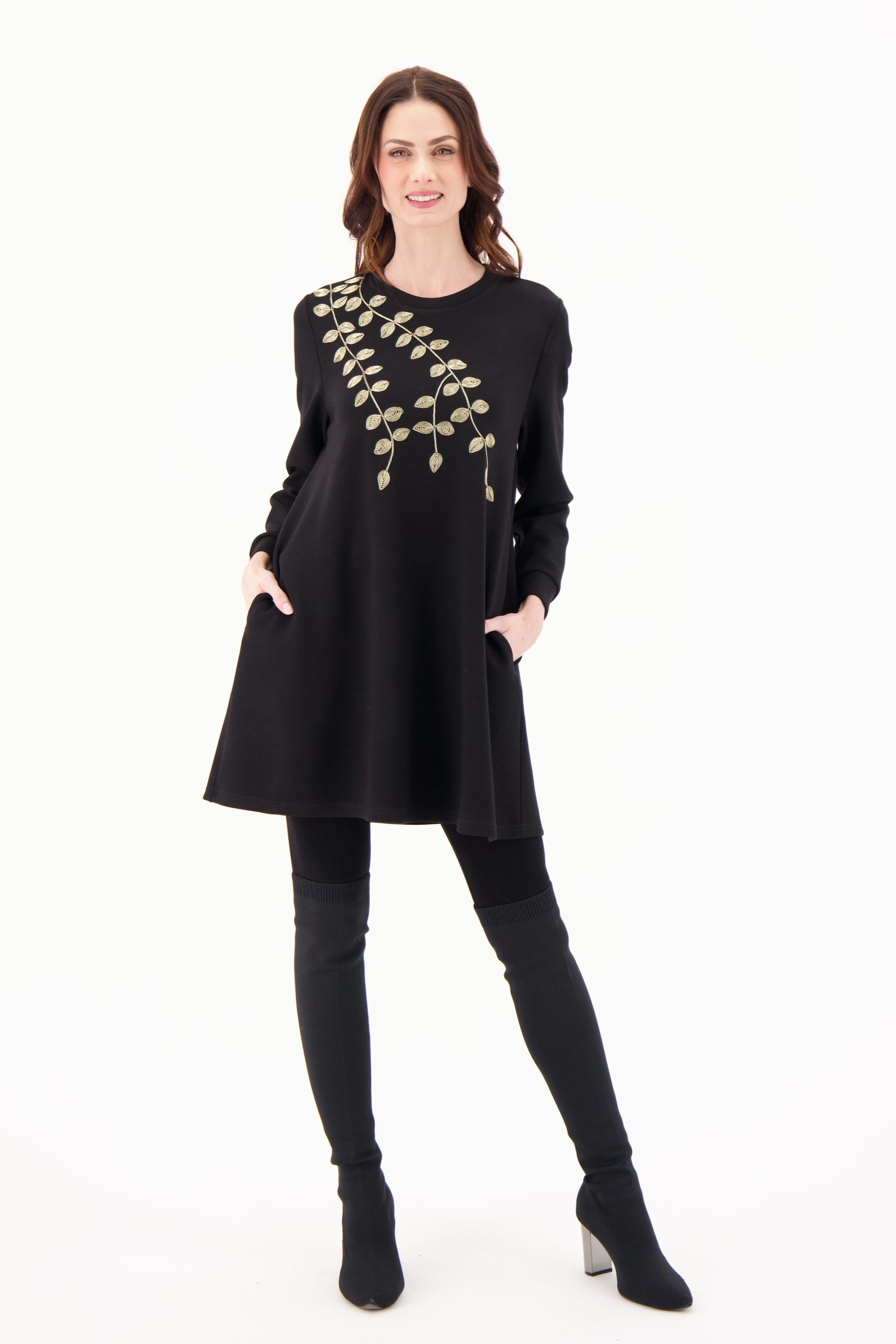 Woman wearing a black dress with gold embroidery on a white background