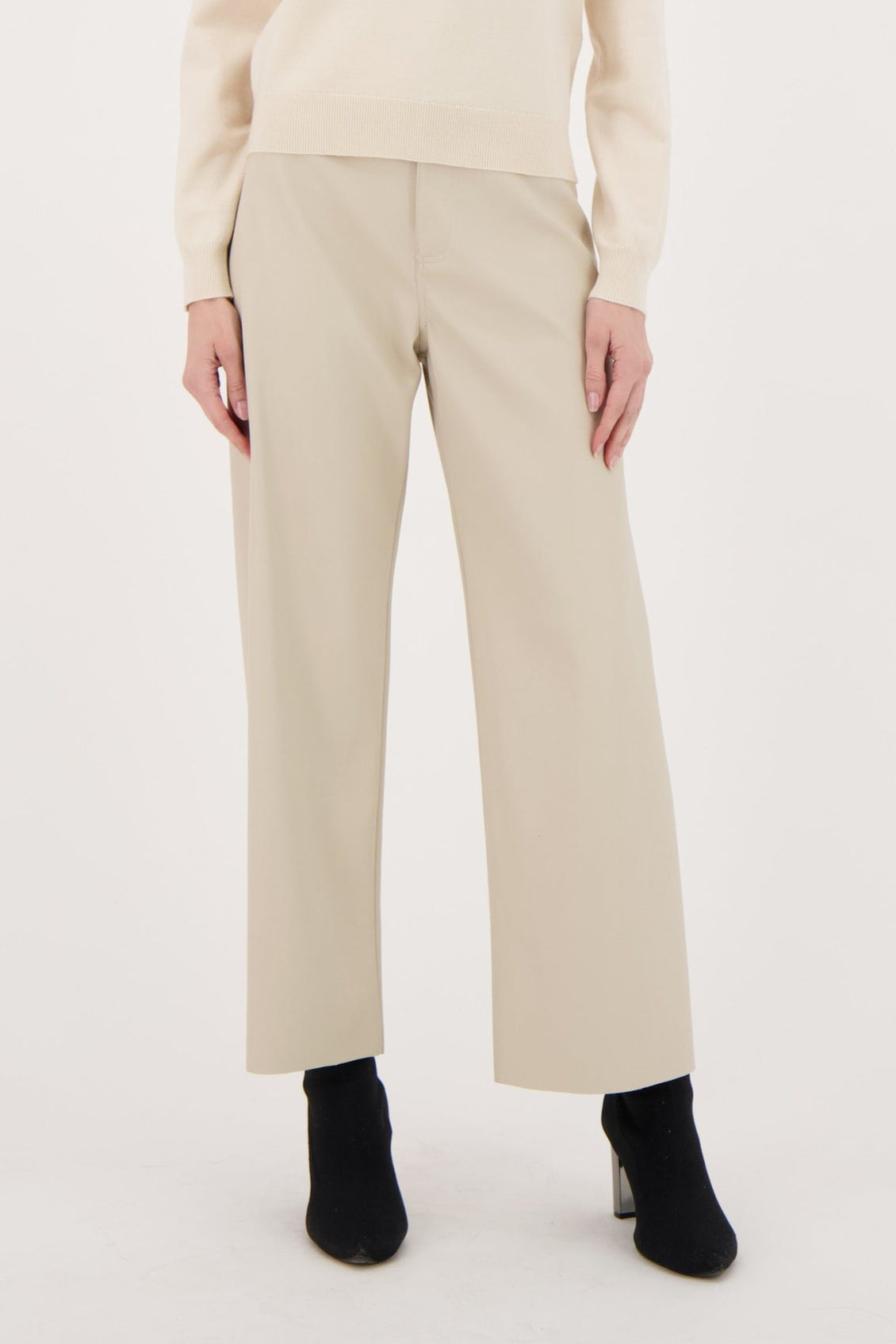 Woman wearing a beige sweater and pants on a white background
