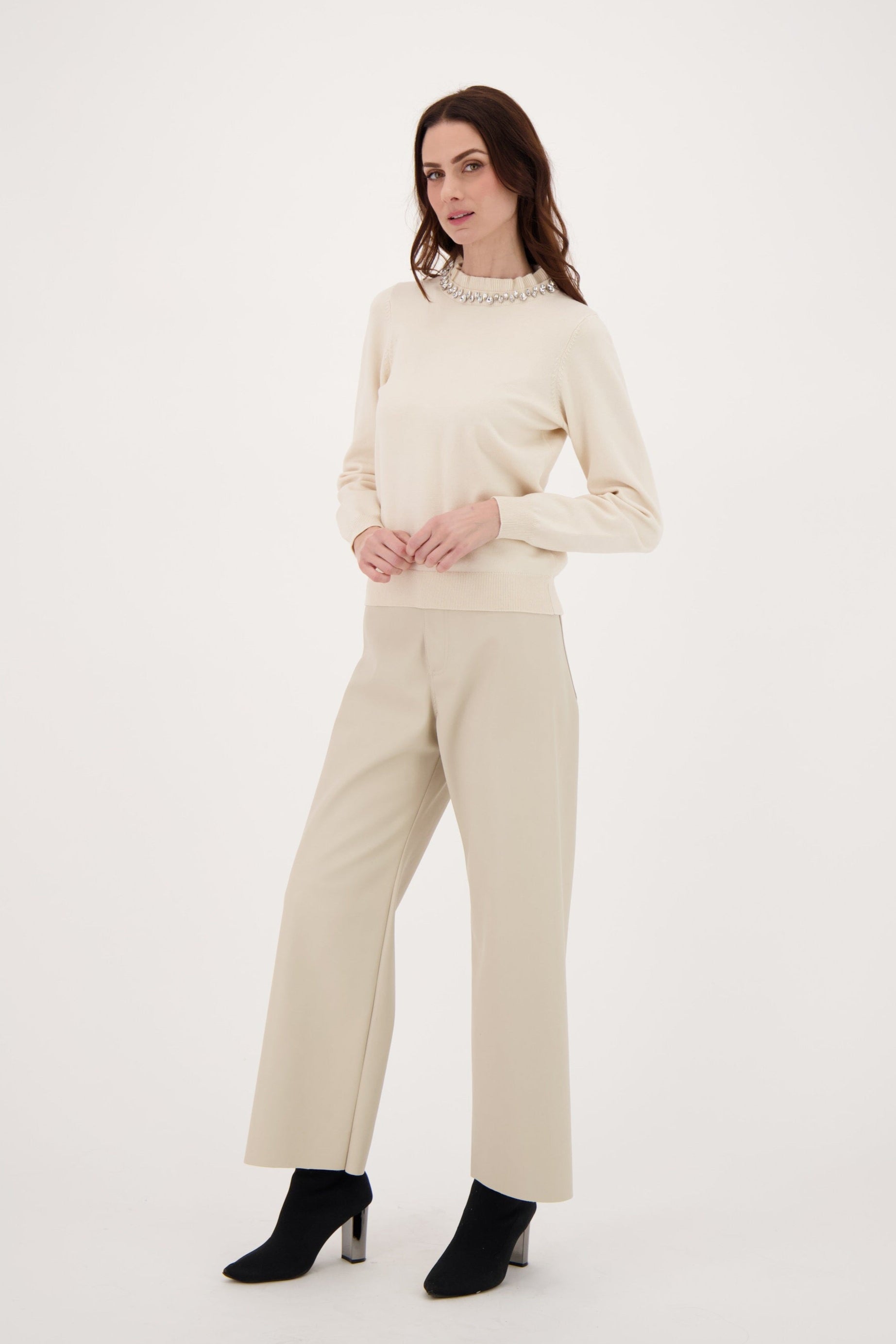 Woman wearing a beige sweater and pants on a white background