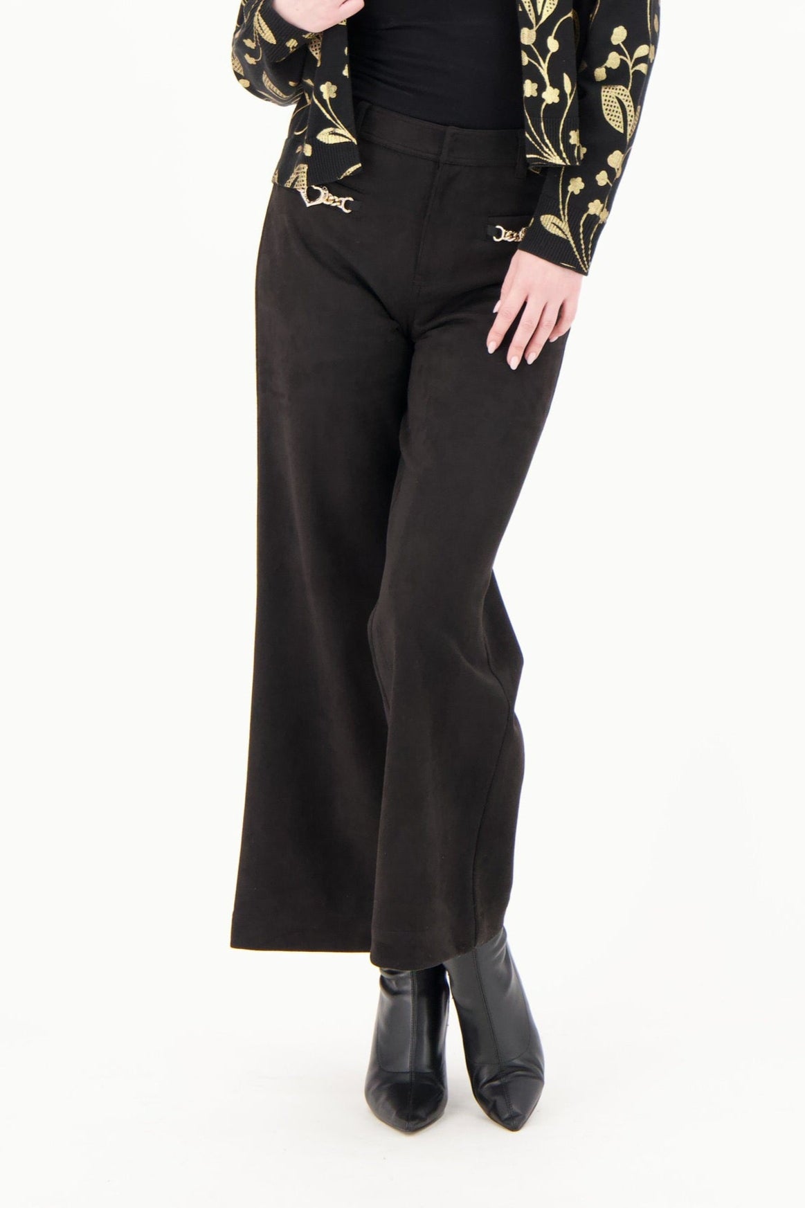 Woman wearing a black and gold patterned jacket with black pants on a white background