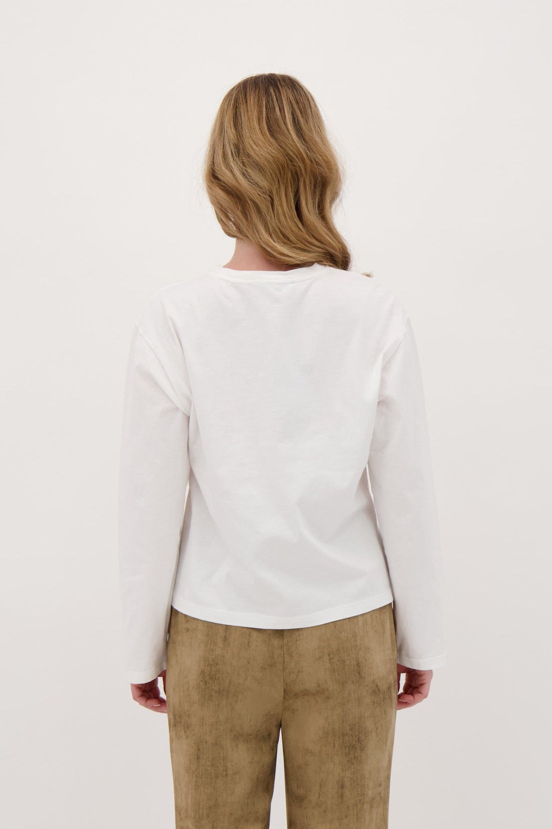 Person wearing a white sweater and beige pants on a white background
