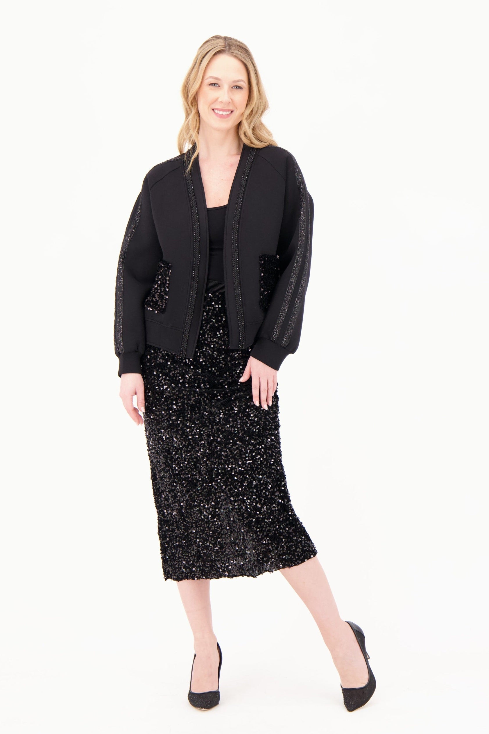 Woman wearing a black blazer and black dress with sequins on a white background