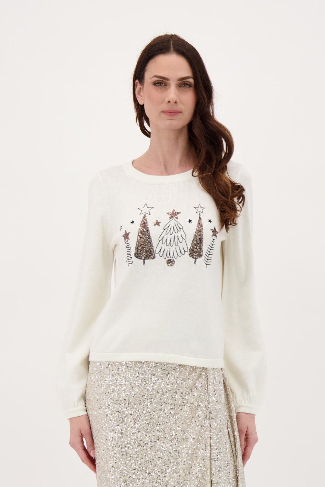 Woman wearing a white sweater with Christmas tree design on a plain background
