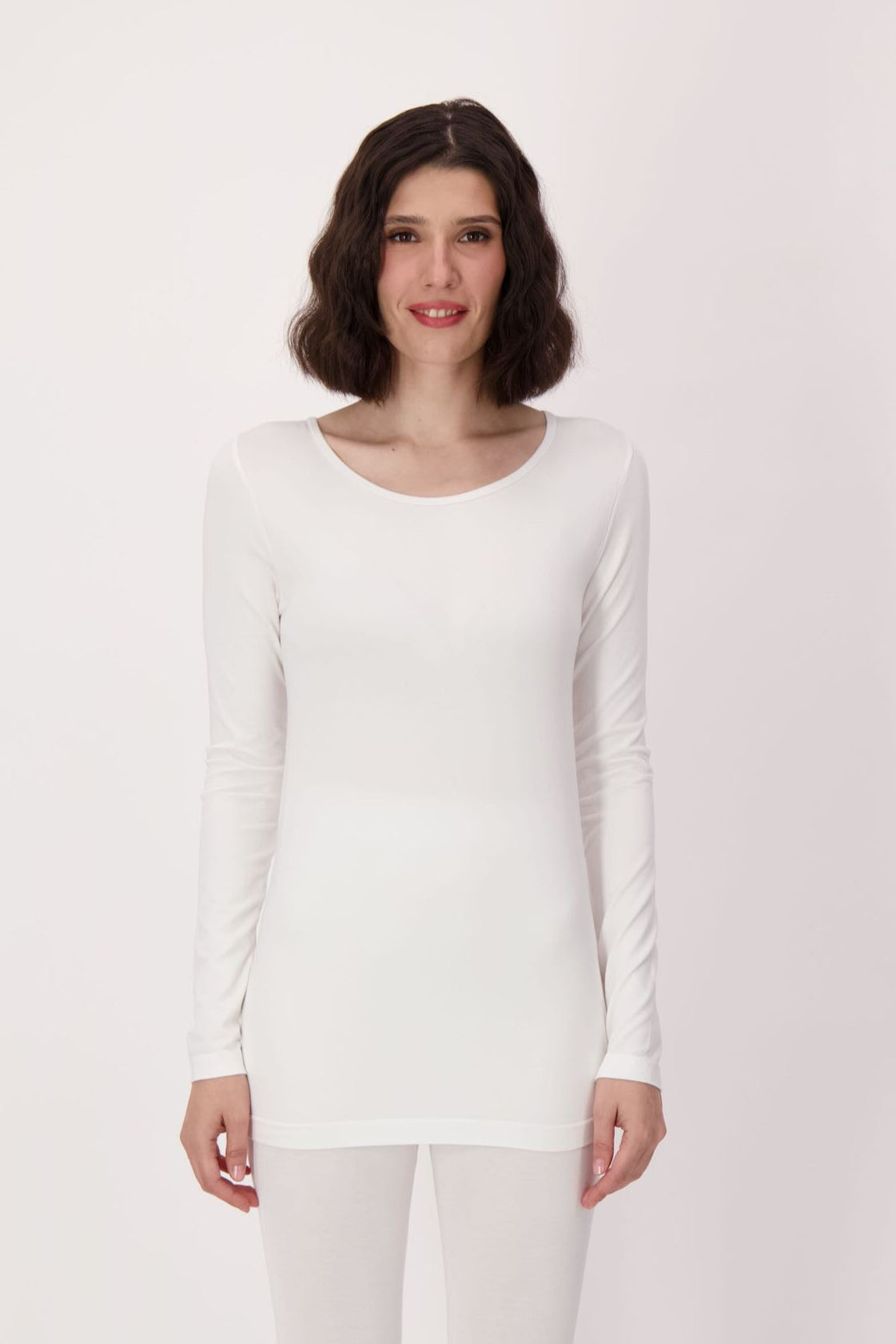Woman wearing a white long-sleeve top and pants on a white background