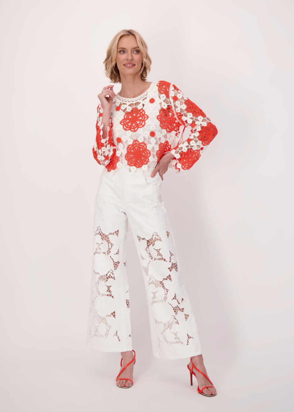 Woman wearing a white outfit with red floral embroidery on a white background