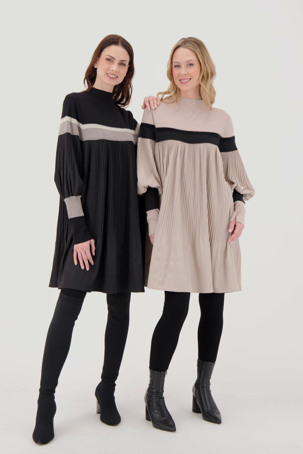 Two women wearing black and beige long-sleeve dresses on a white background