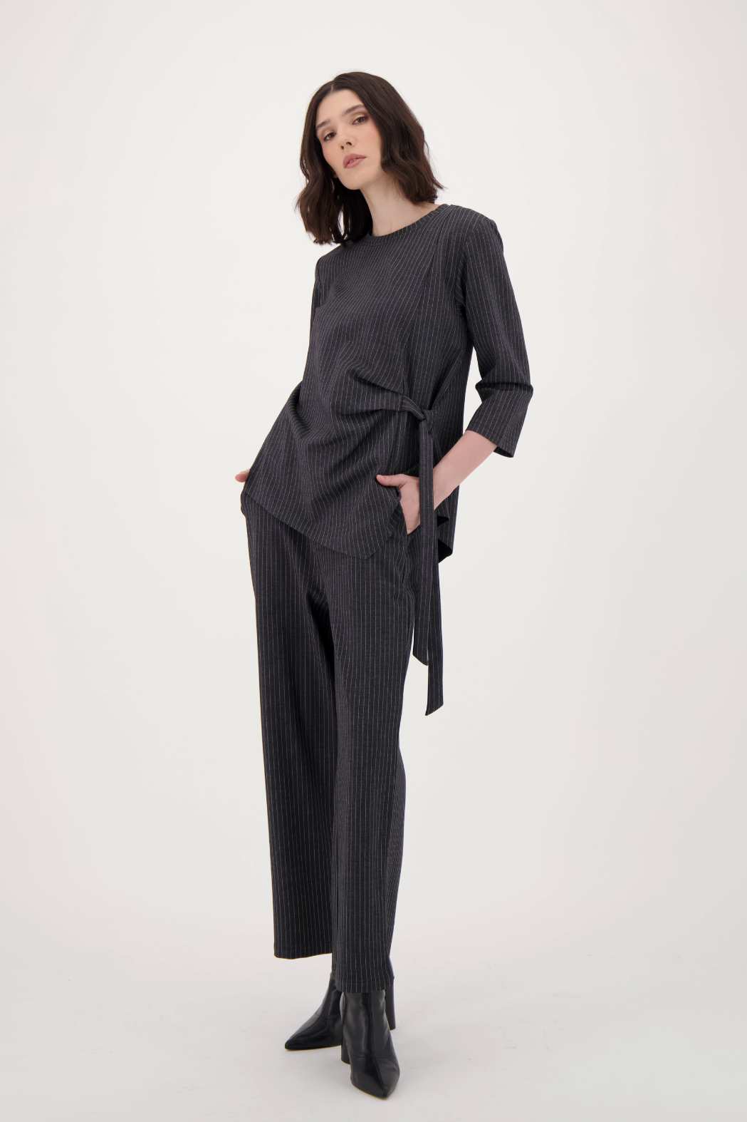 Woman wearing a black outfit with a belt on a white background