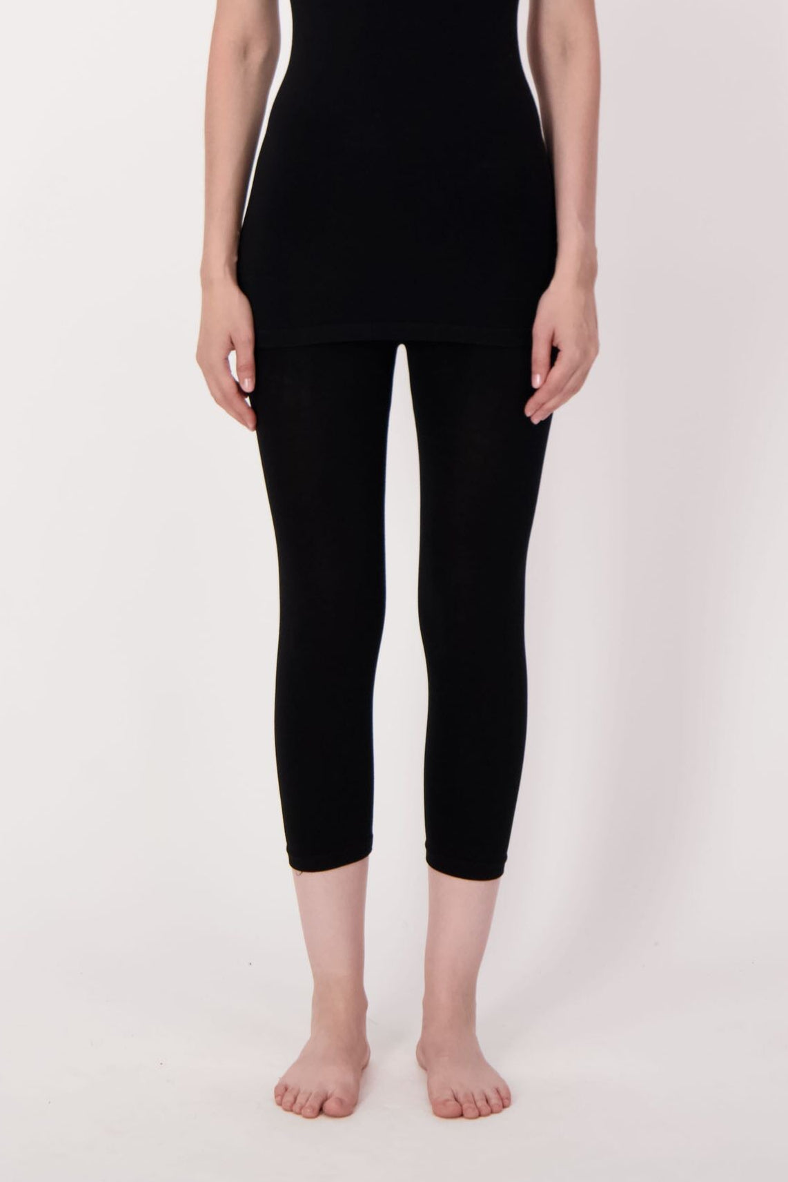 Person wearing a black tank top and black capri pants on a white background