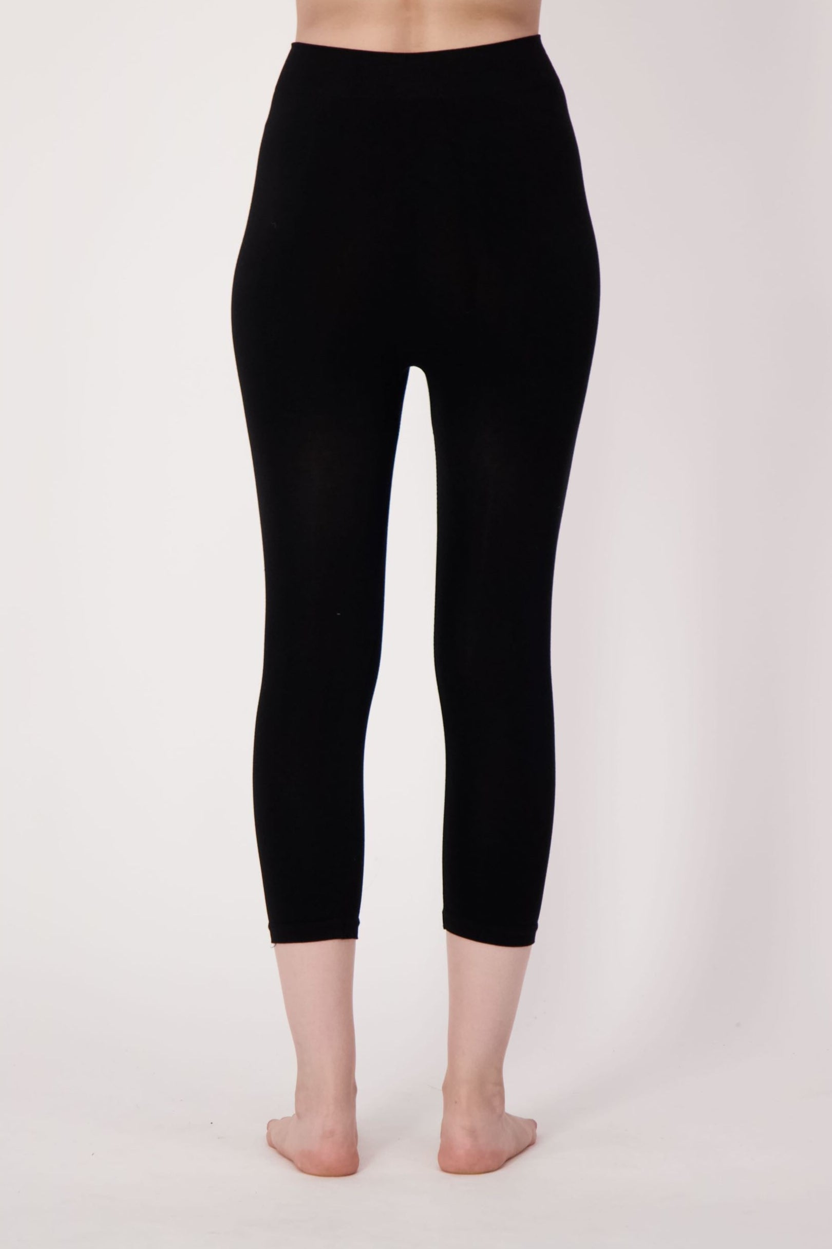 Person wearing black leggings on a plain background
