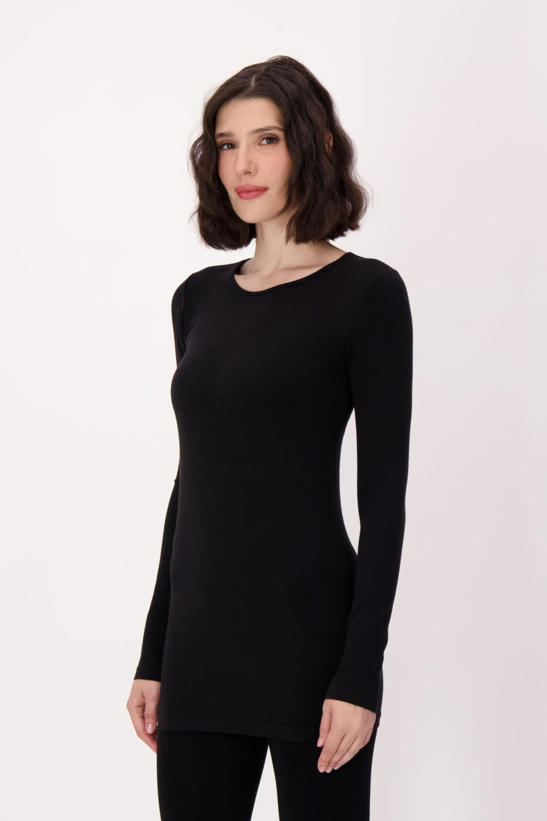 Person wearing a black long-sleeve top and leggings on a white background