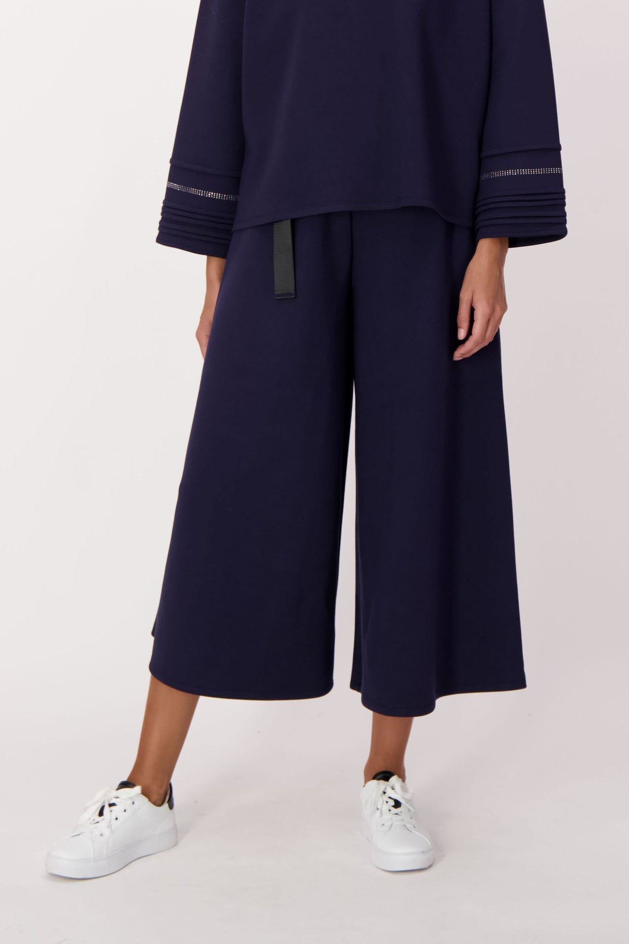Woman wearing a navy outfit with wide-leg pants on a white background