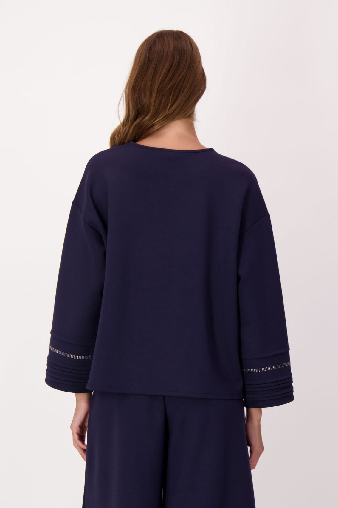 Woman wearing a navy blue outfit with wide-leg pants on a white background