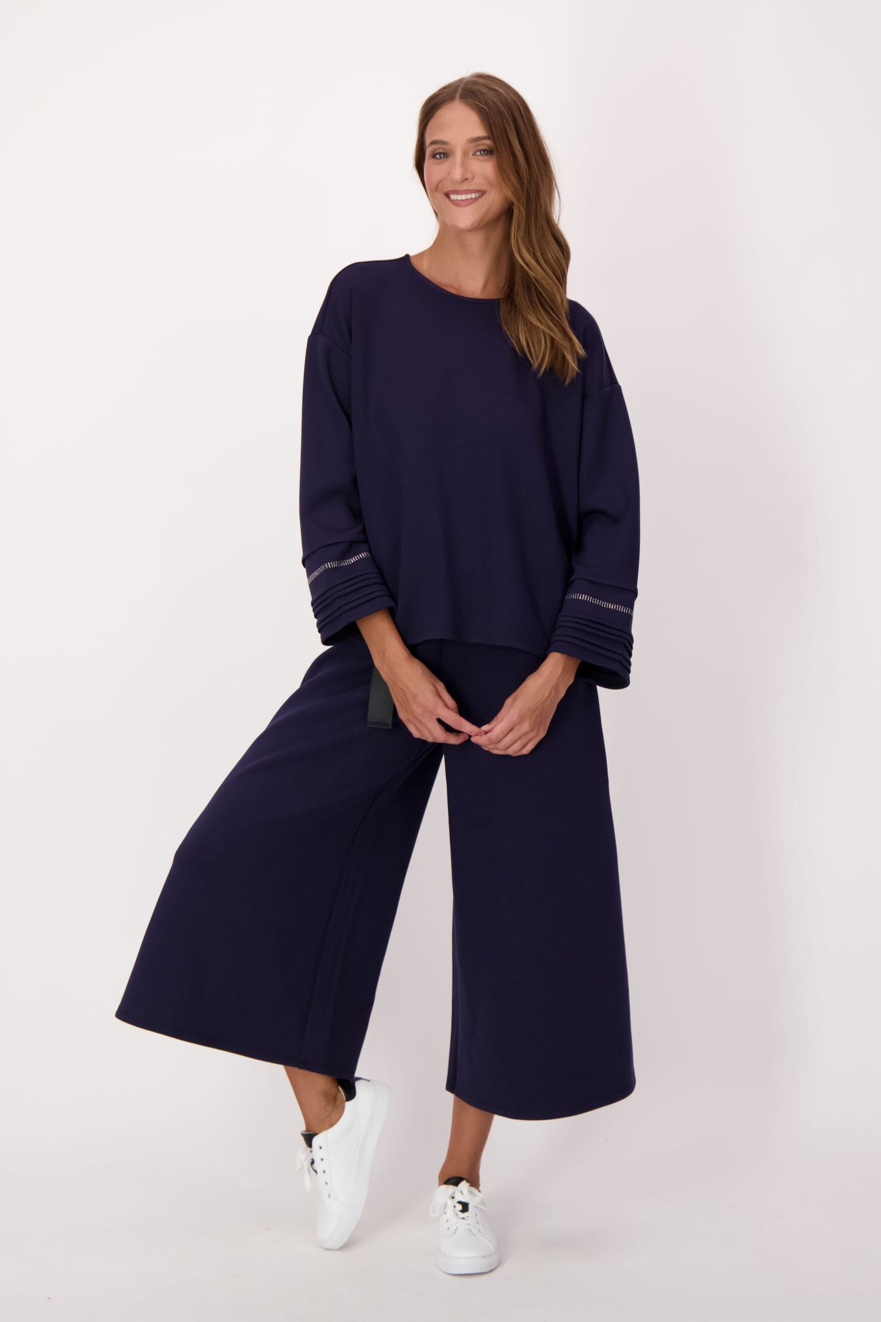 Woman wearing a navy outfit with wide-leg pants on a white background