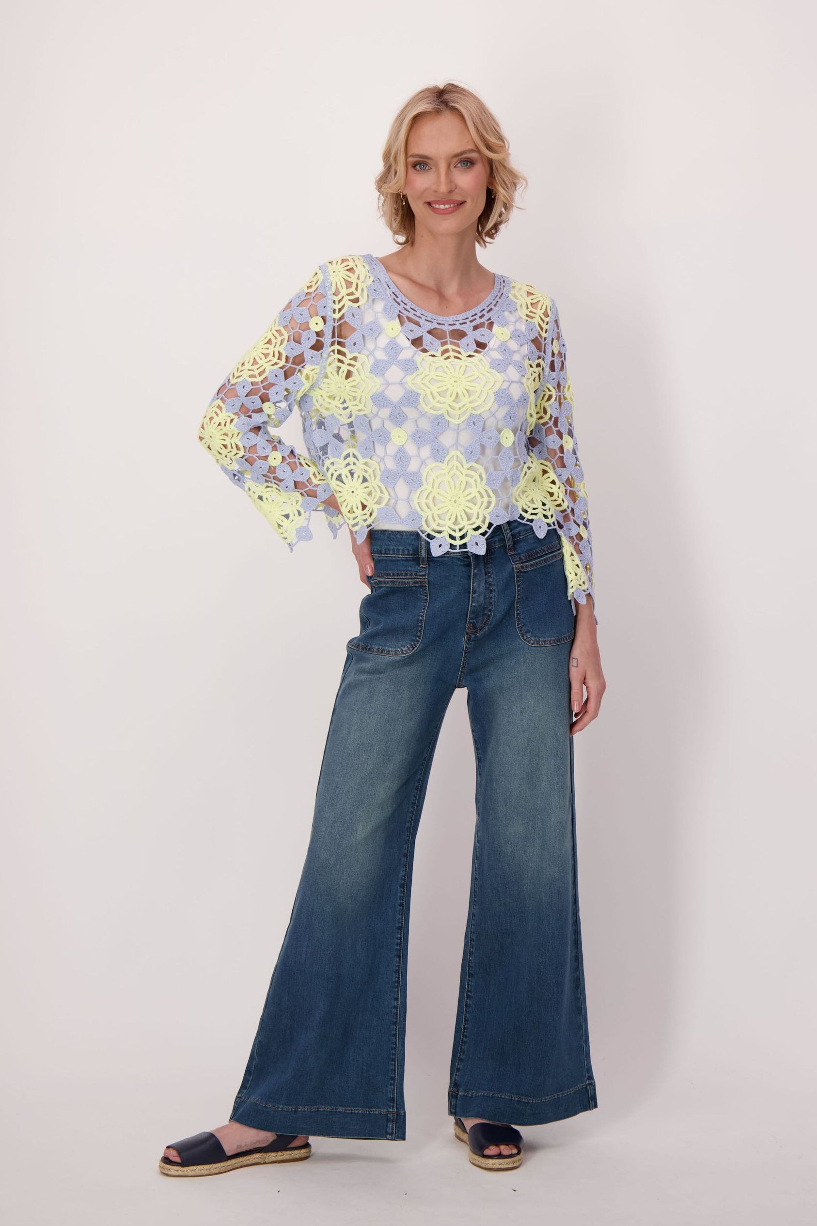 Woman wearing a floral blouse and blue jeans on a white background