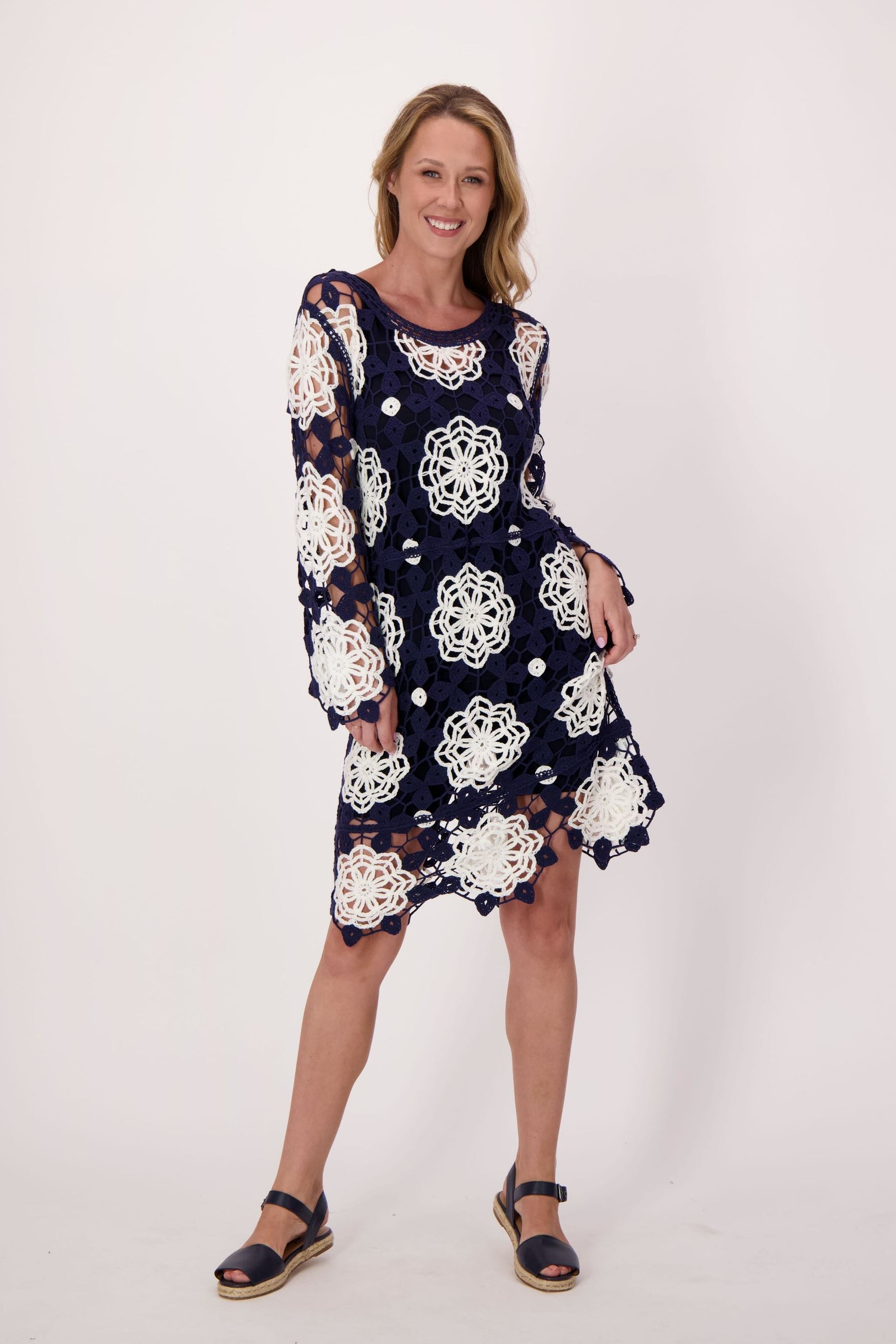 Woman wearing a navy dress with white floral pattern on a plain background