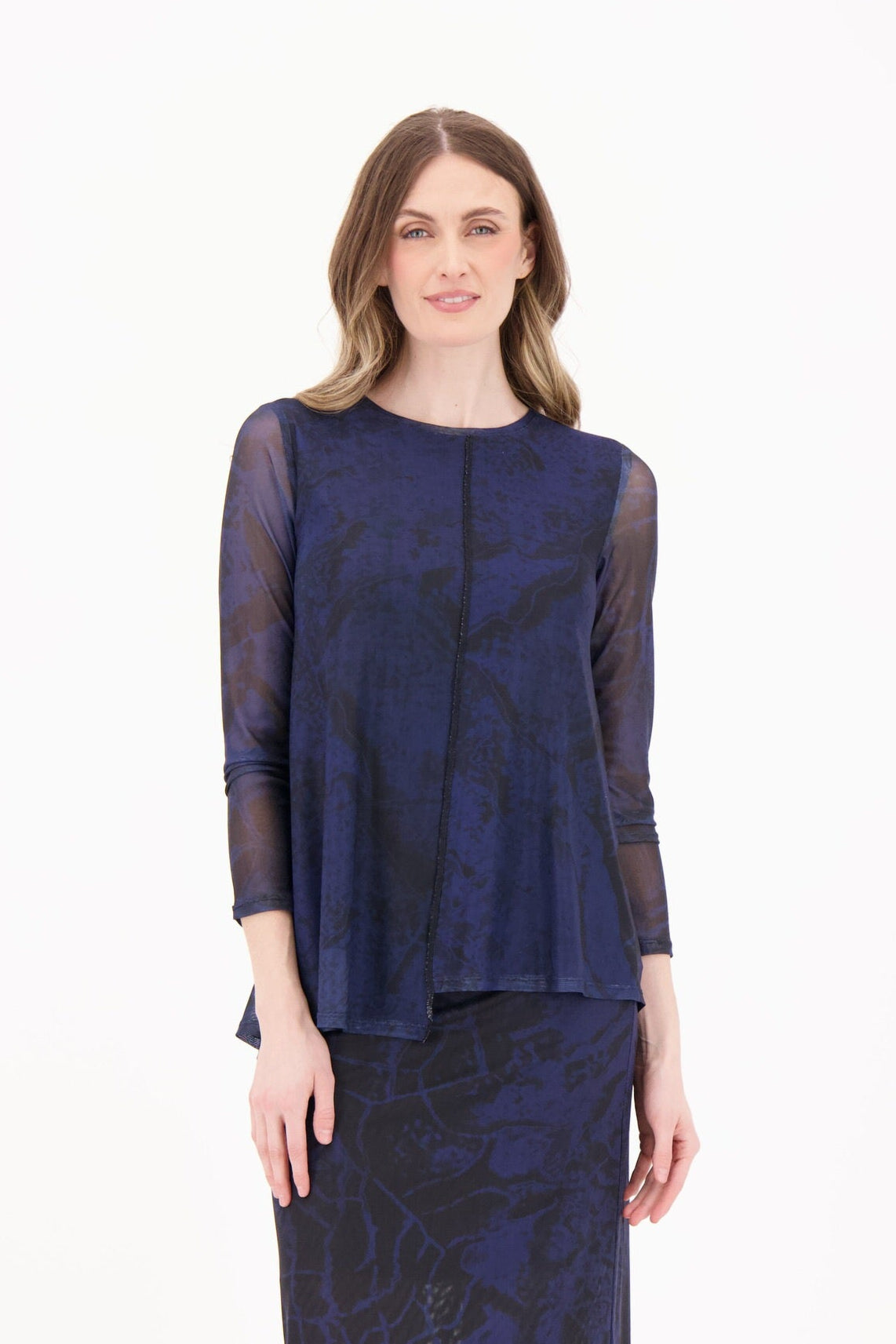 Woman wearing a navy blue dress with sheer sleeves on a white background