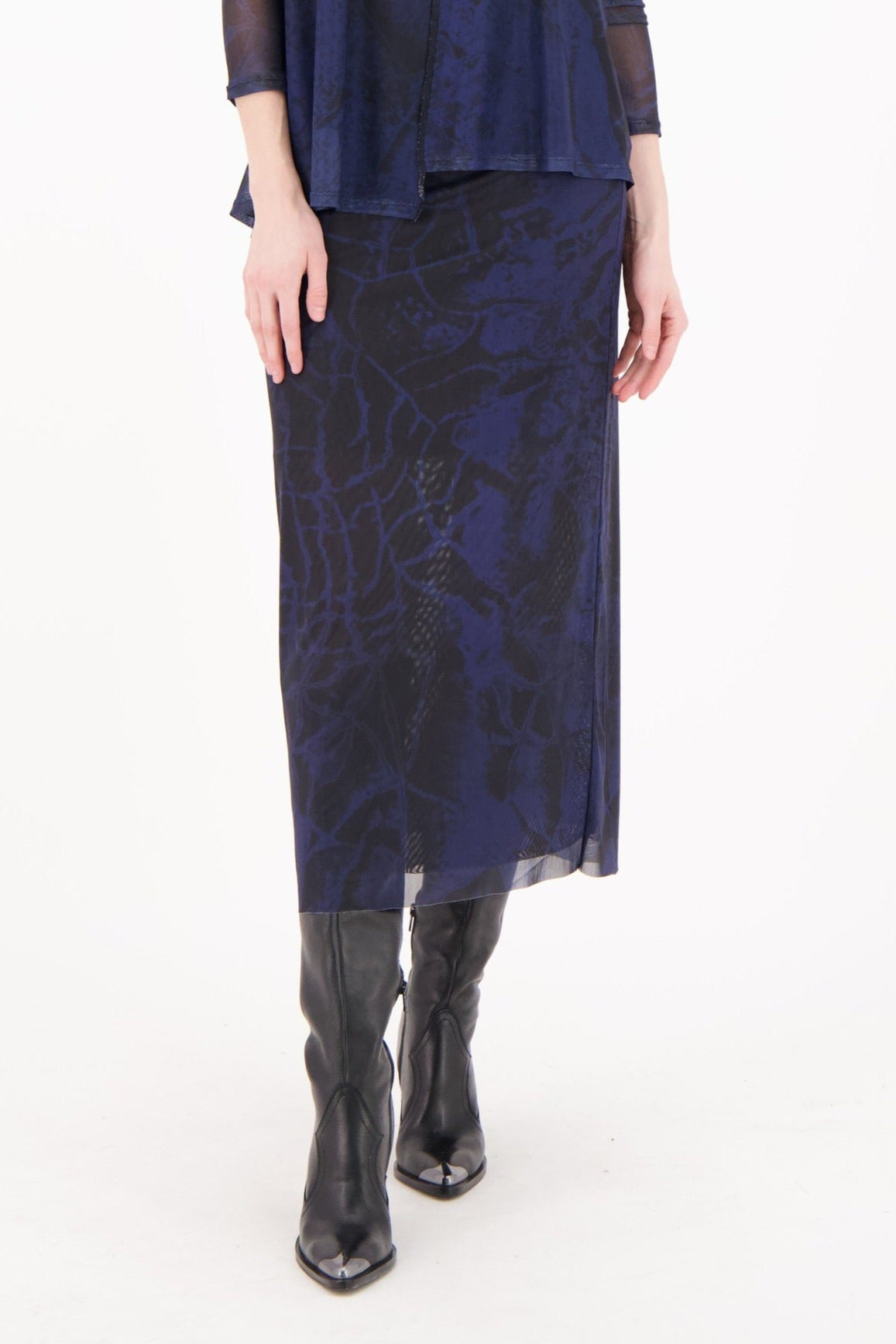 Woman wearing a navy blue dress with sheer sleeves on a white background