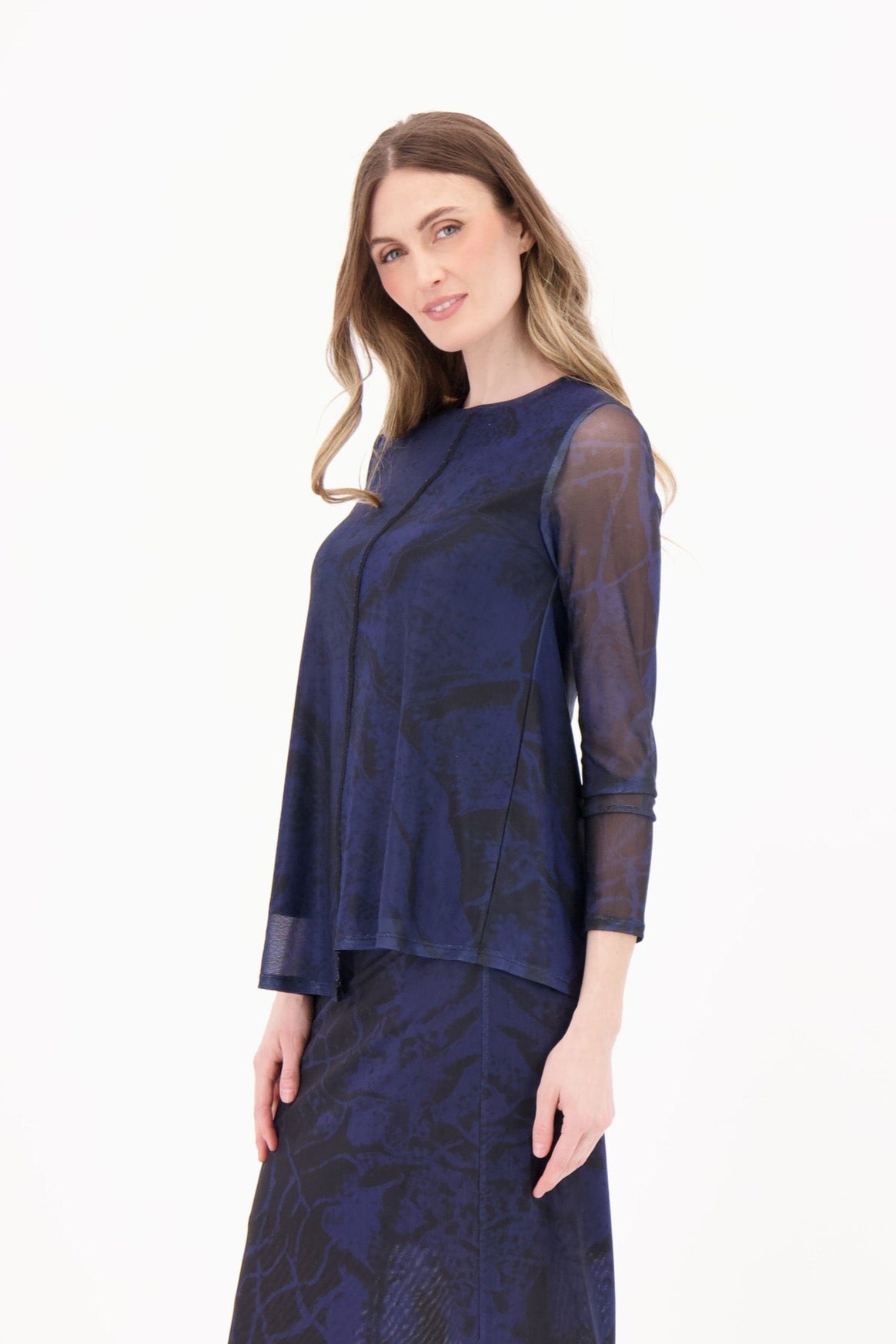 Woman wearing a navy blue dress with sheer sleeves on a white background